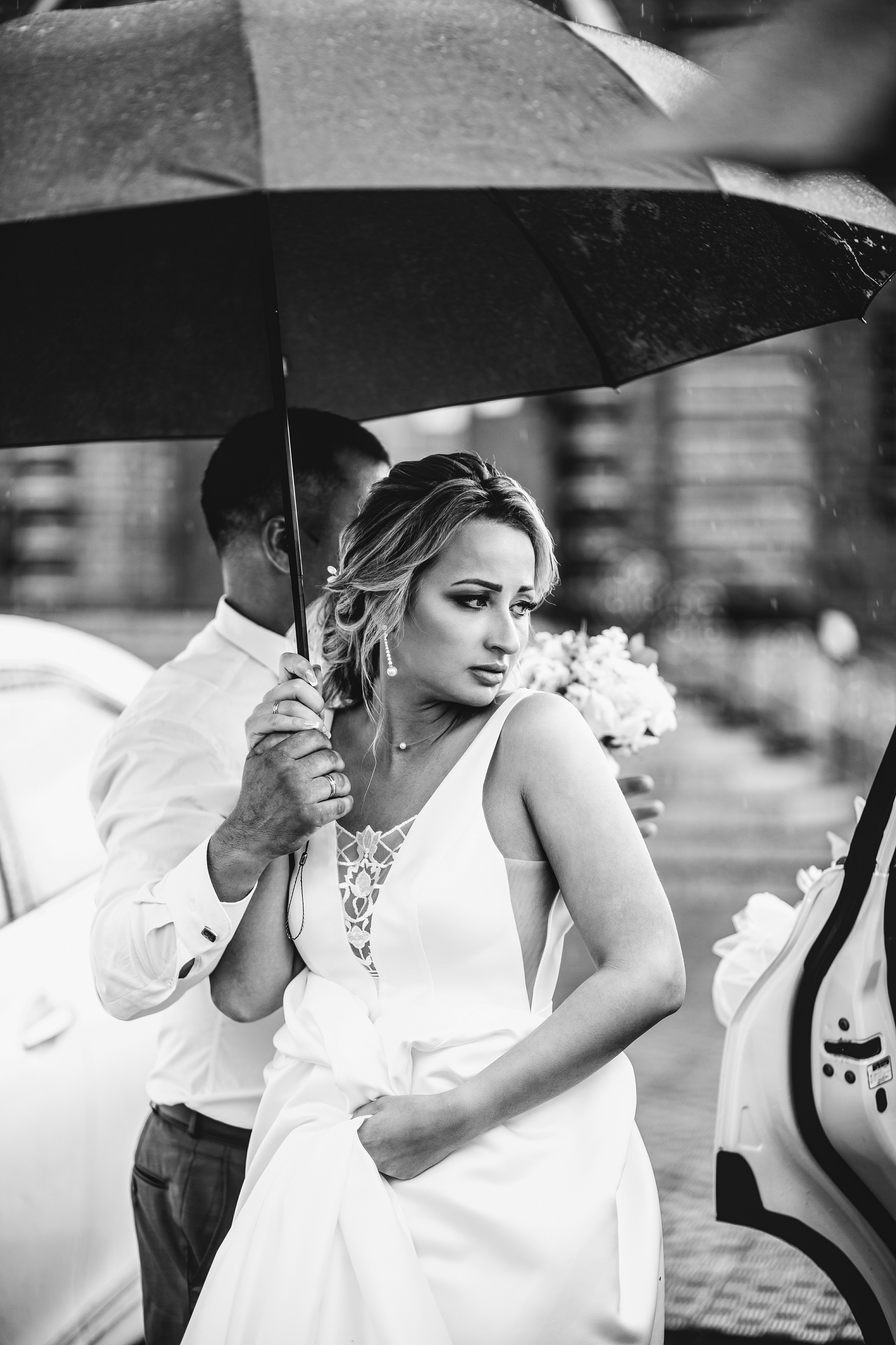 Невеста выходит из машины жених придерживает зонт идёт дождь в чб чёрно-белая фотография стильная свадебная фотография во Владивостоке