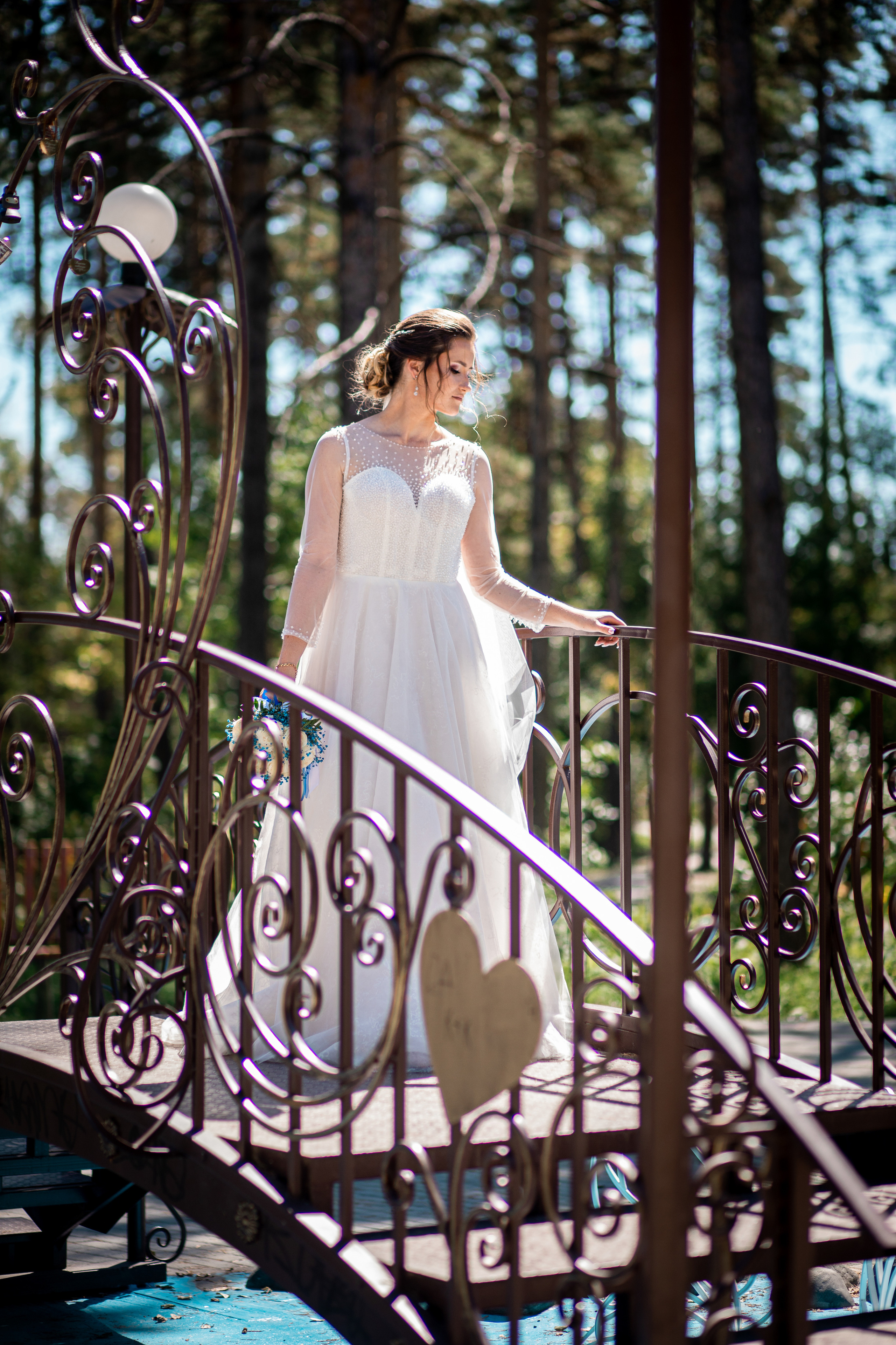 Высокая невеста идёт по металлическому мосту в Парке Лазо Спасск-Дальний