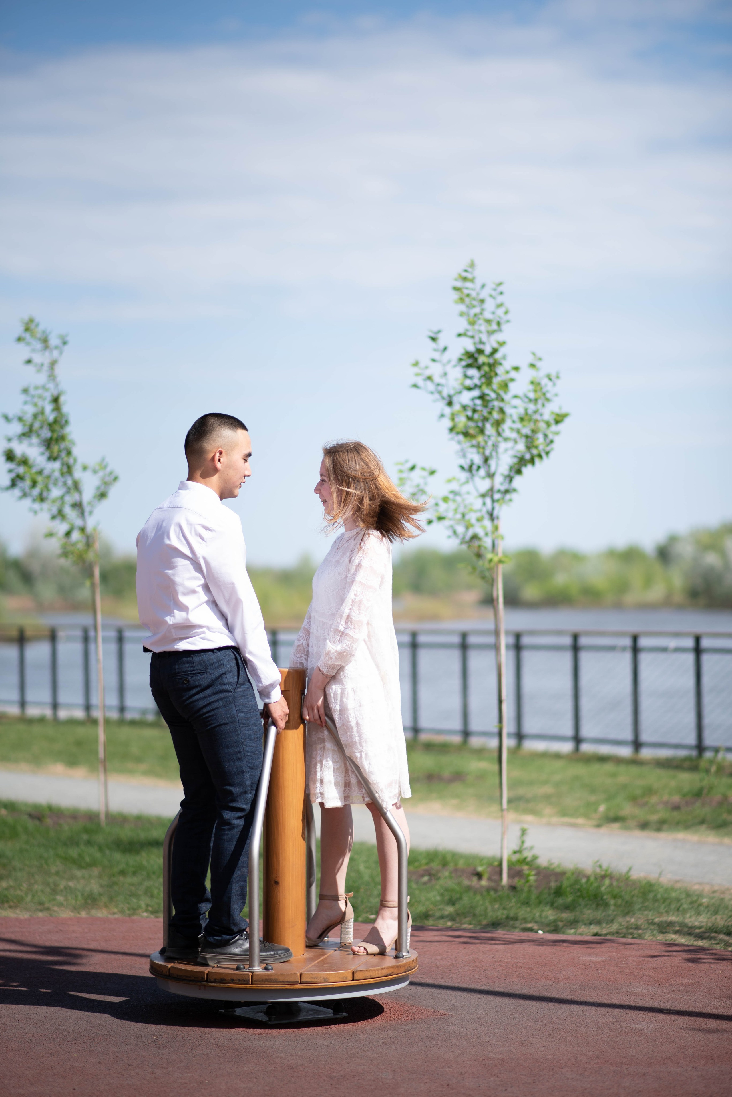 Влюбленная пара катается на карусели летом.