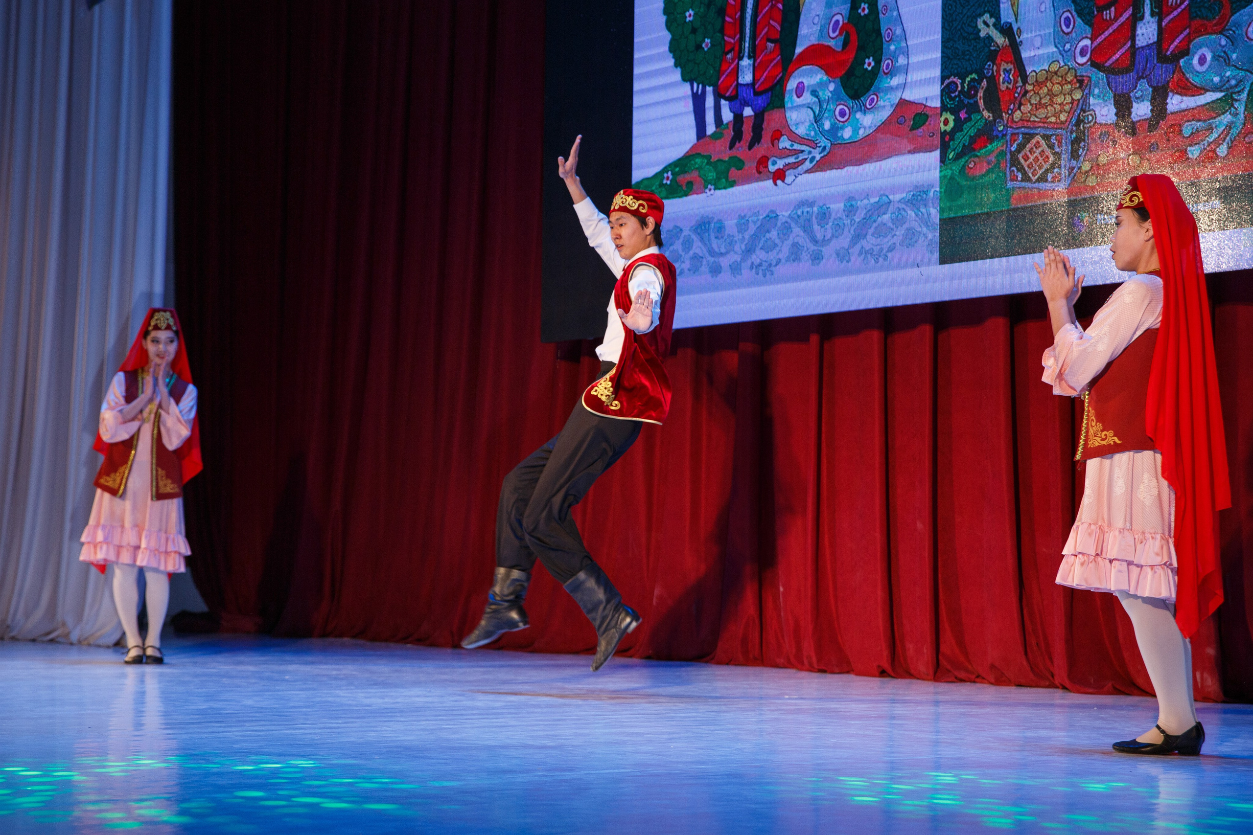 Артисты в народных костюмах исполняют танец на сцене.