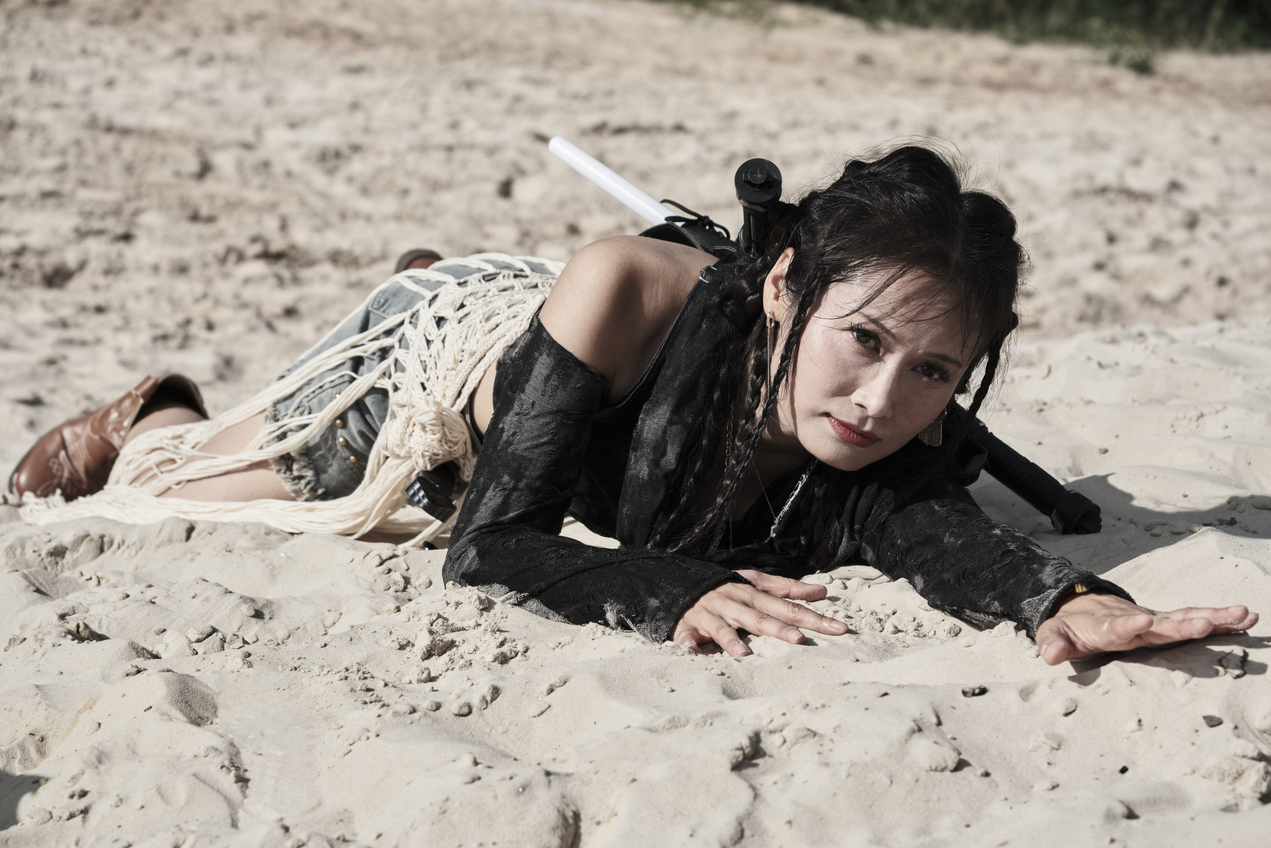 Девушка азиатской внешности ползет по песку