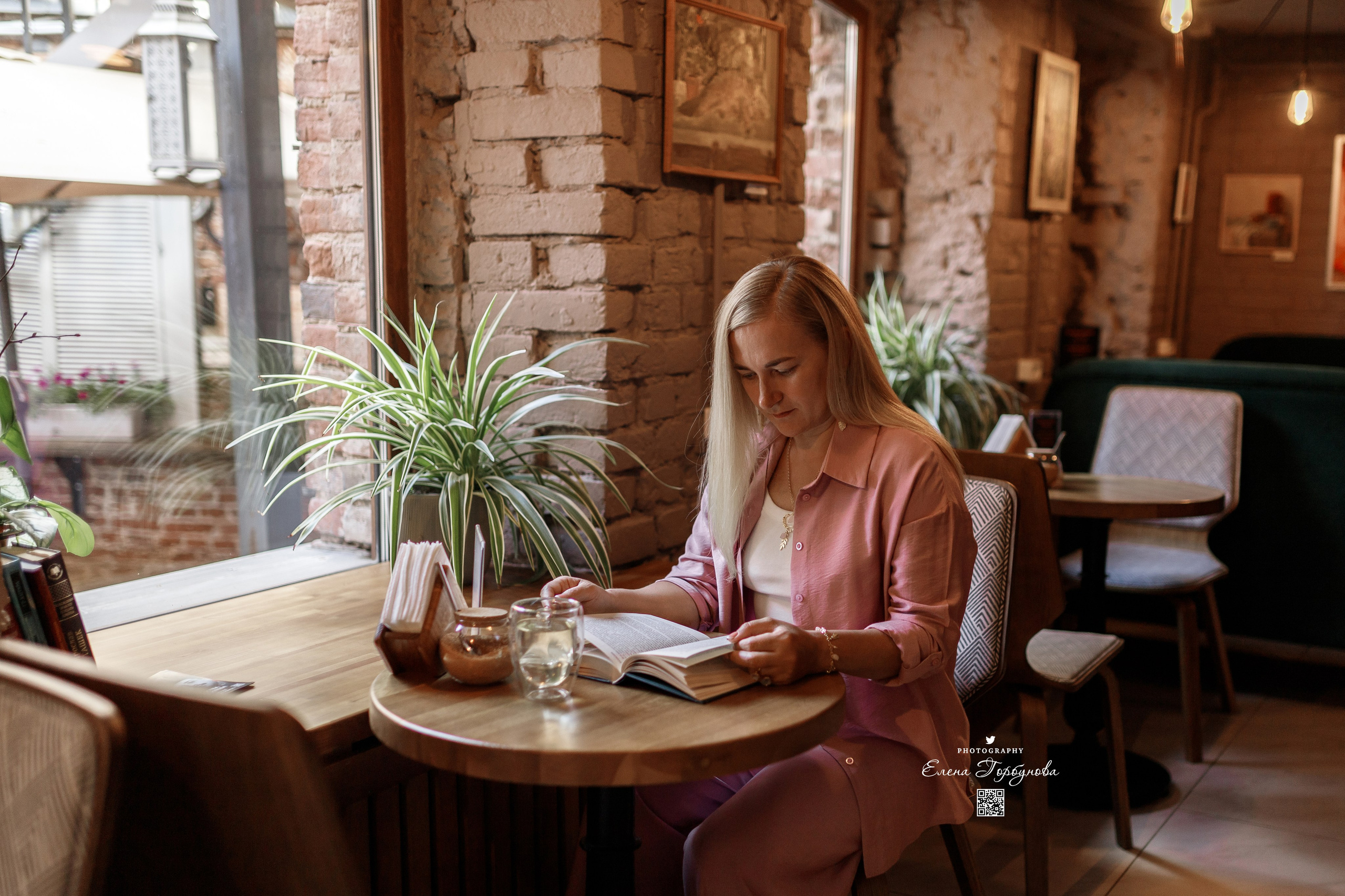 Девушка в кафе читает книгу, на фотосессии