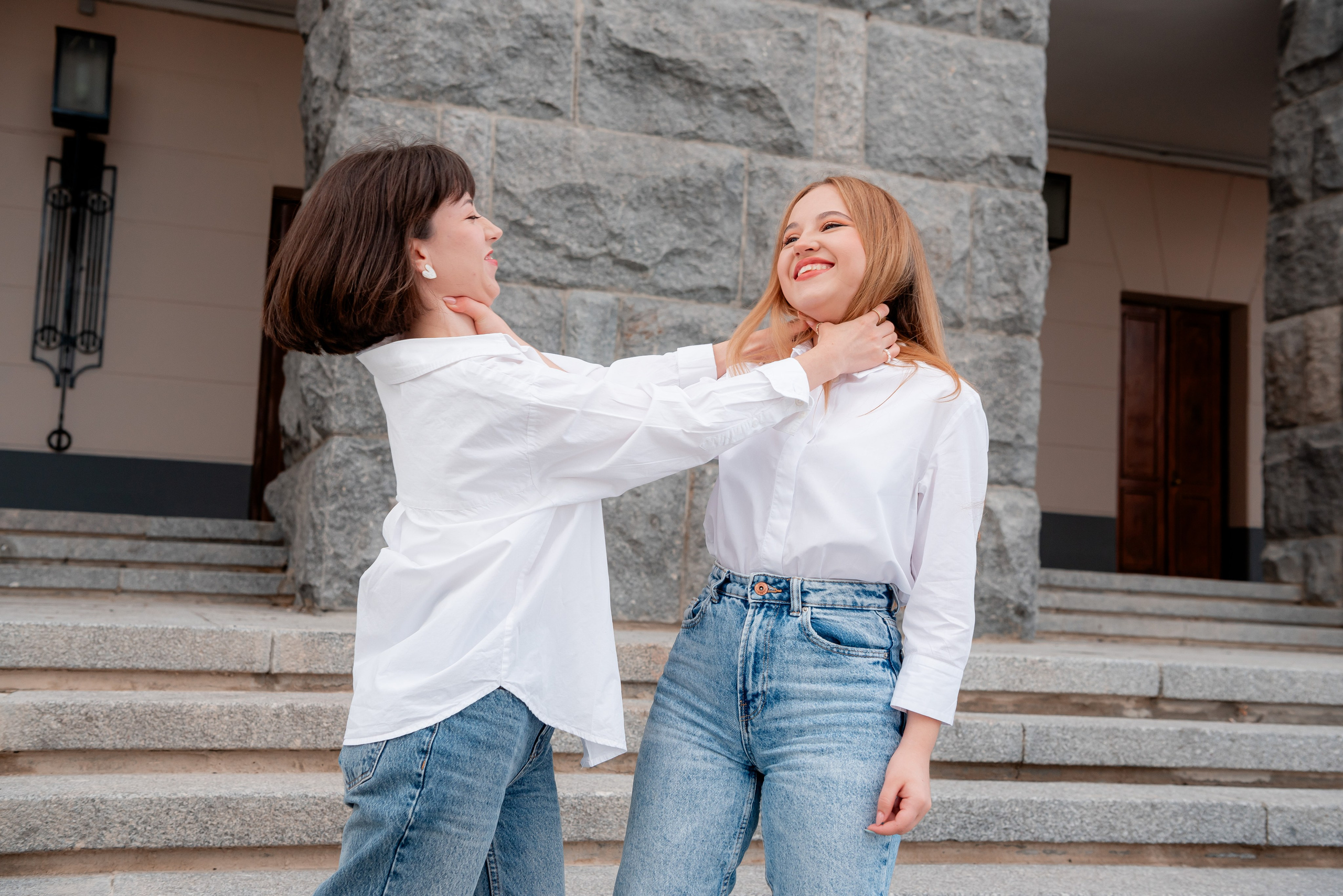 Фото на улице города две сестры в одеты и белые верх и джинсы синие балуются душа друг друга