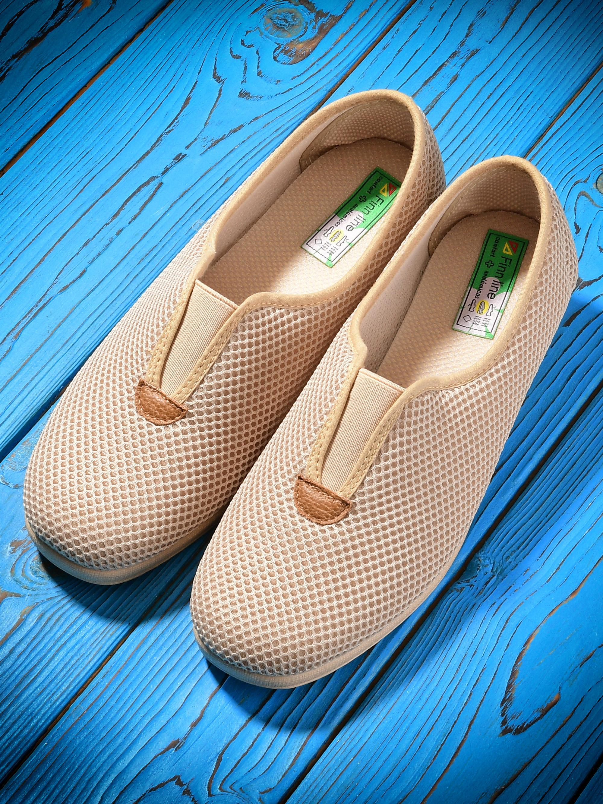 Туфли бежевого цвета на синем деревянном фоне.
