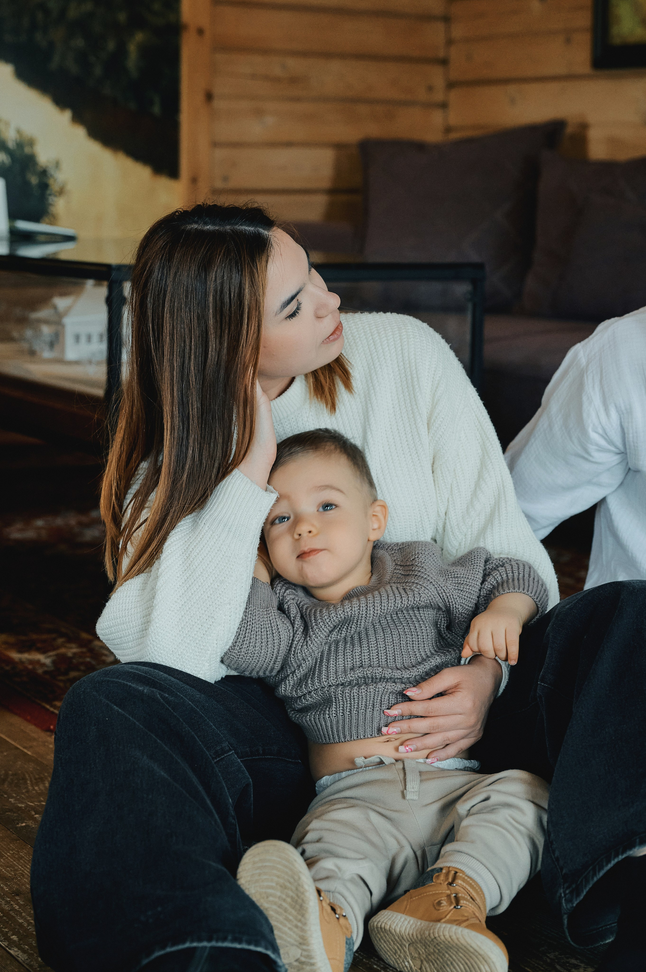 Мать держит сына у себя на коленях, мальчик расслабленно лежит, глядя в камеру.