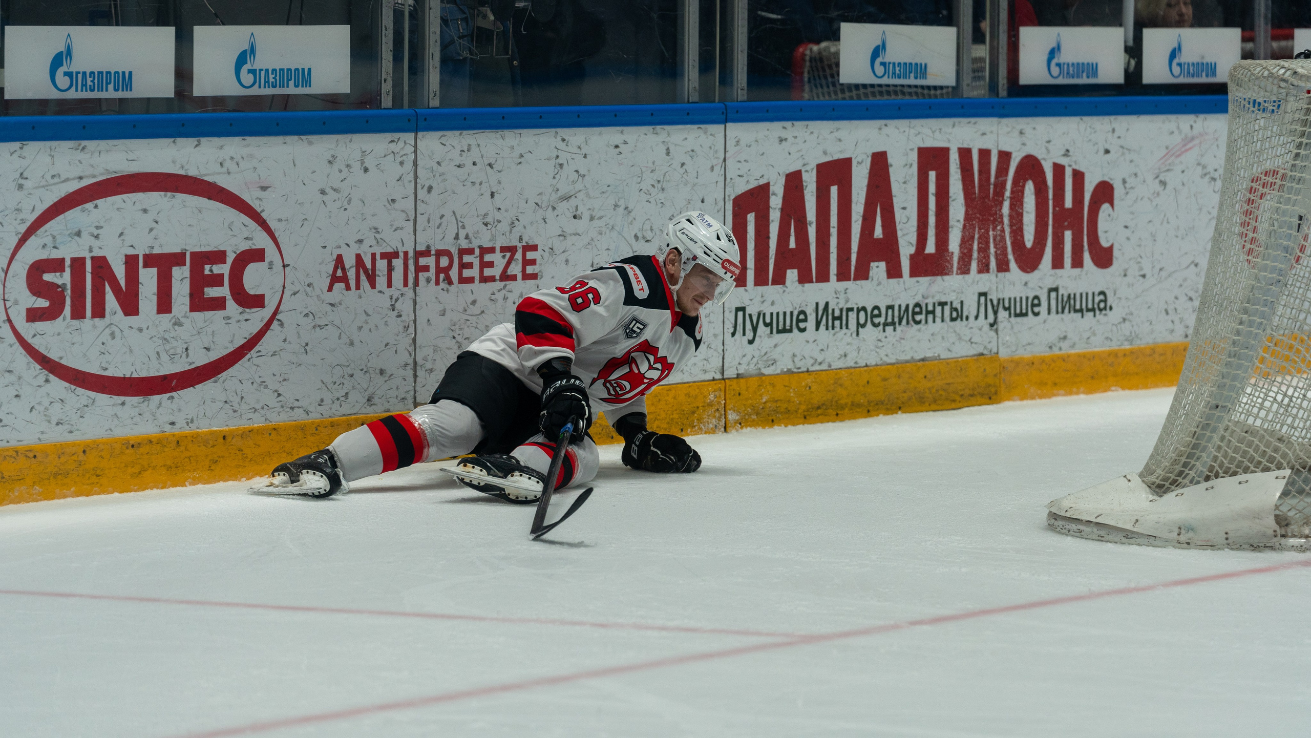 Игрок «Молота» на льду у борта после падения. Спортивная фотосъёмка, репортажный фотограф, матч в Санкт-Петербурге.