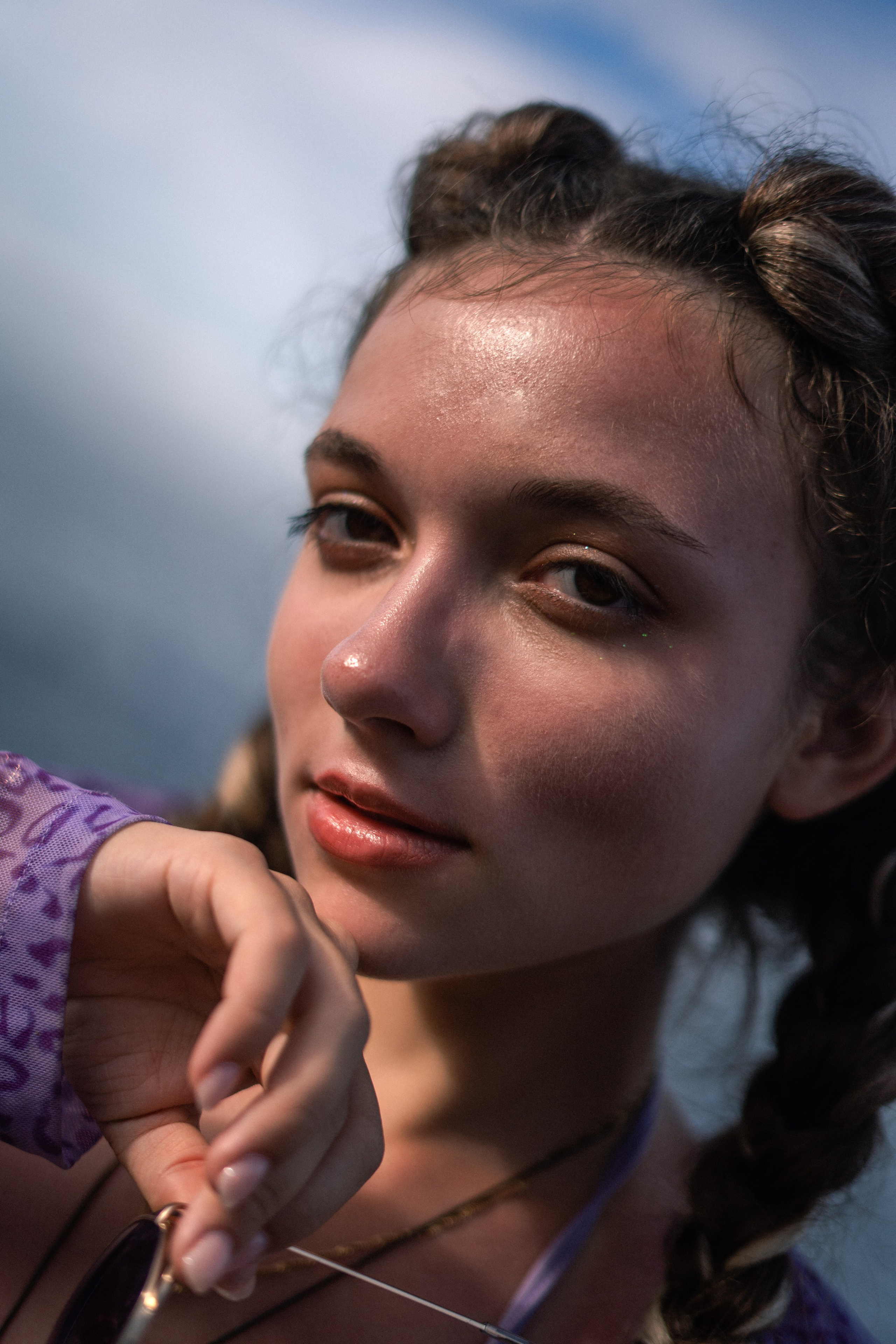 a young girl in a purple swimsuit sitting on the rocks, exposing her legs