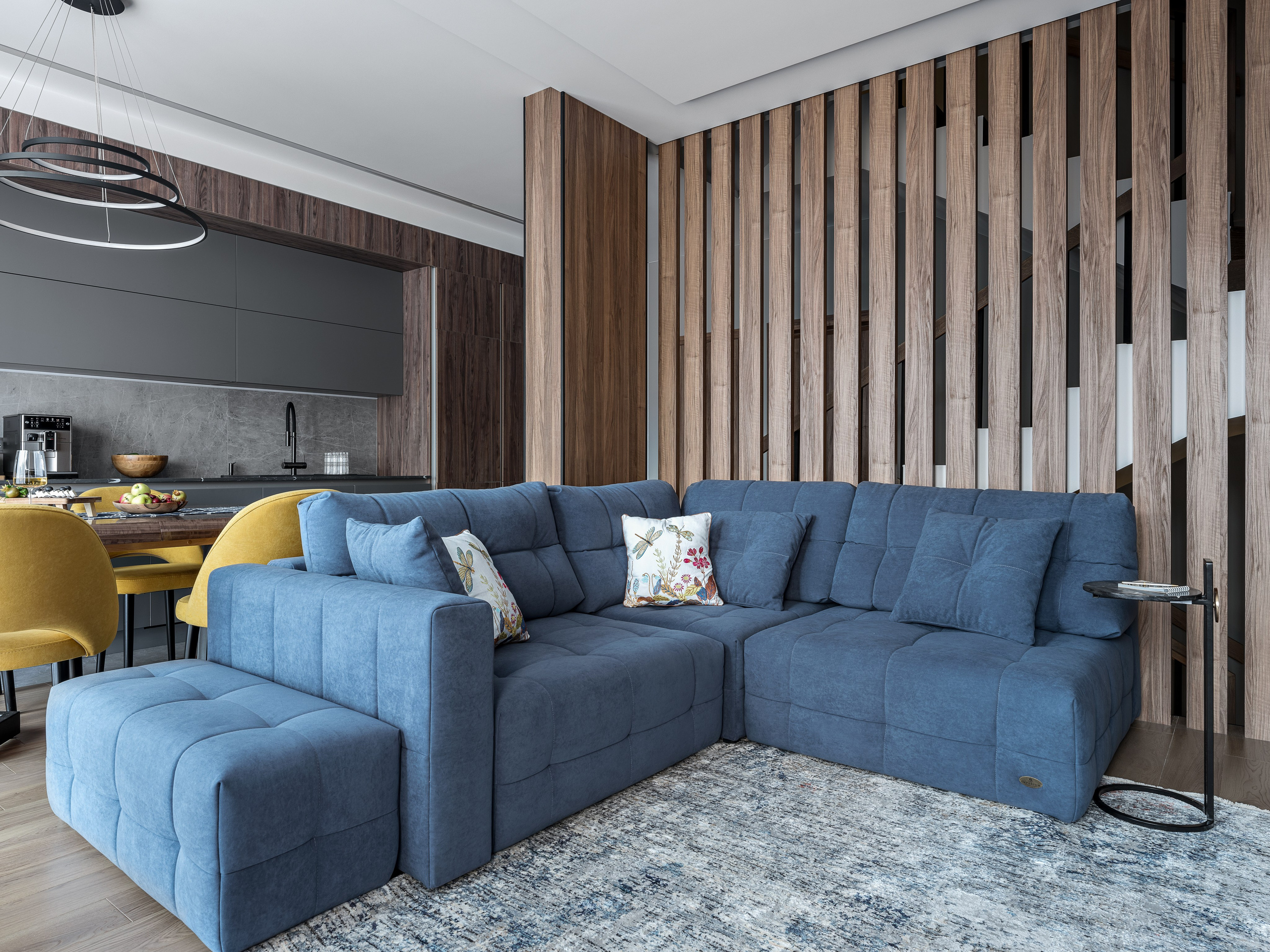 Просторная гостиная с ярким синим диваном и стильной деревянной перегородкой, современный интерьер от дизайнеров Алёны Поповой и Анастасии Дмитриевой, профессиональное фото Сергея Денисенко.