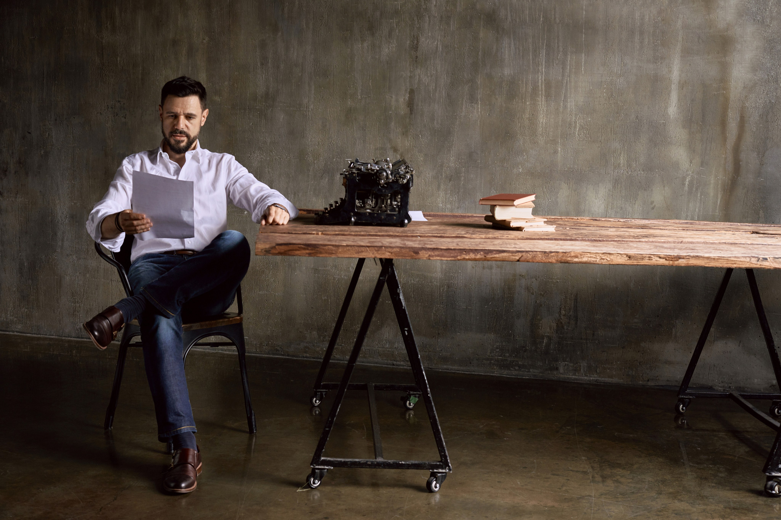 Мужская фотосессия в студии с печатной машинкой за деревянным столом 