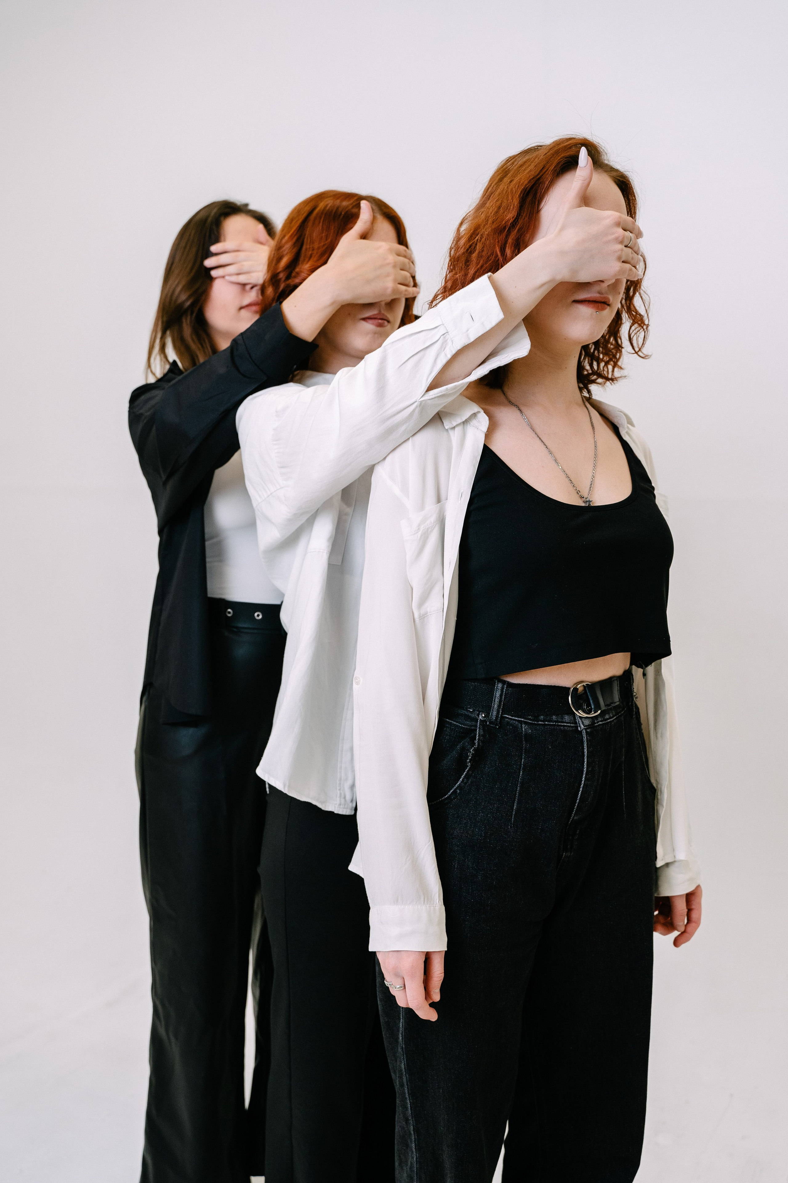 три девушки закрывают друг другу глаза в белой фотостудии 