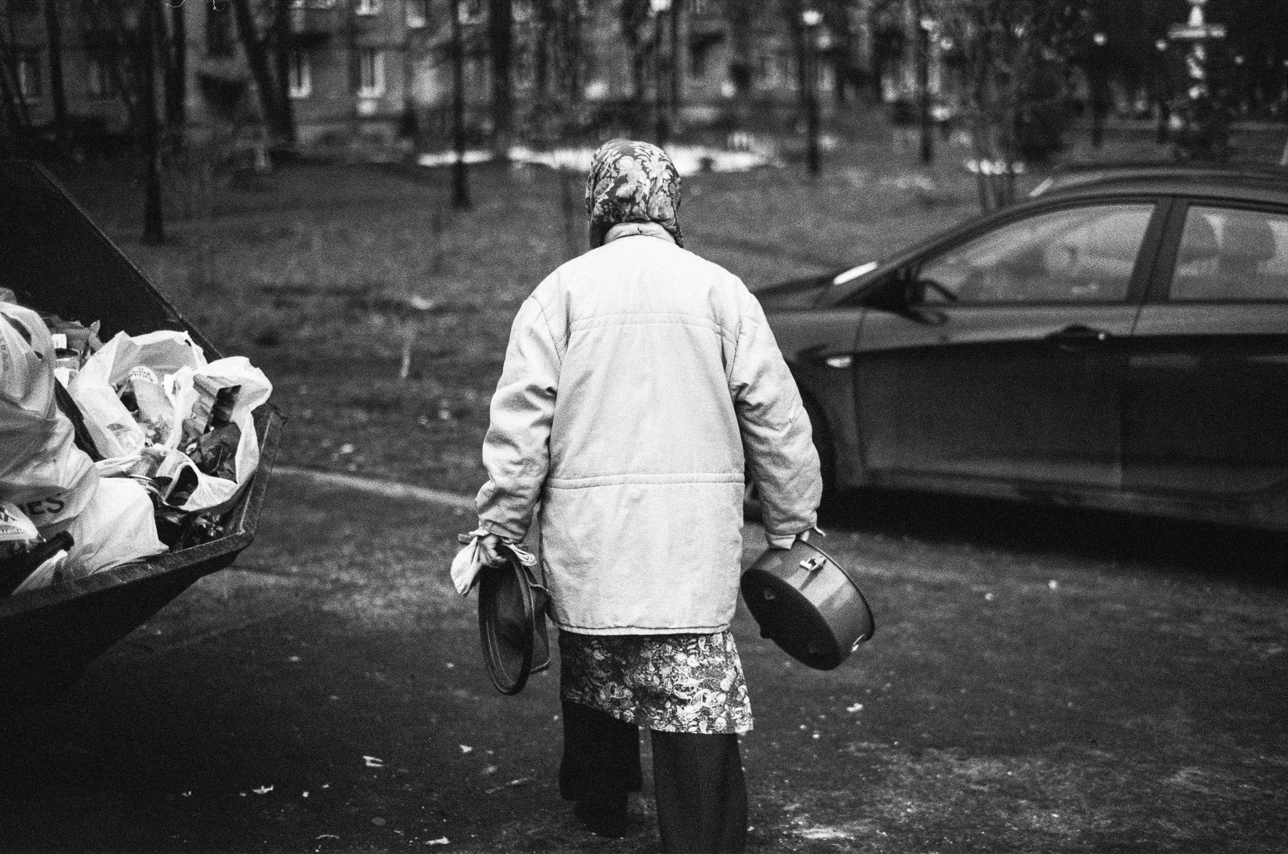 черно белое фото бабушка уходит от помойки  в руках старый пылесос