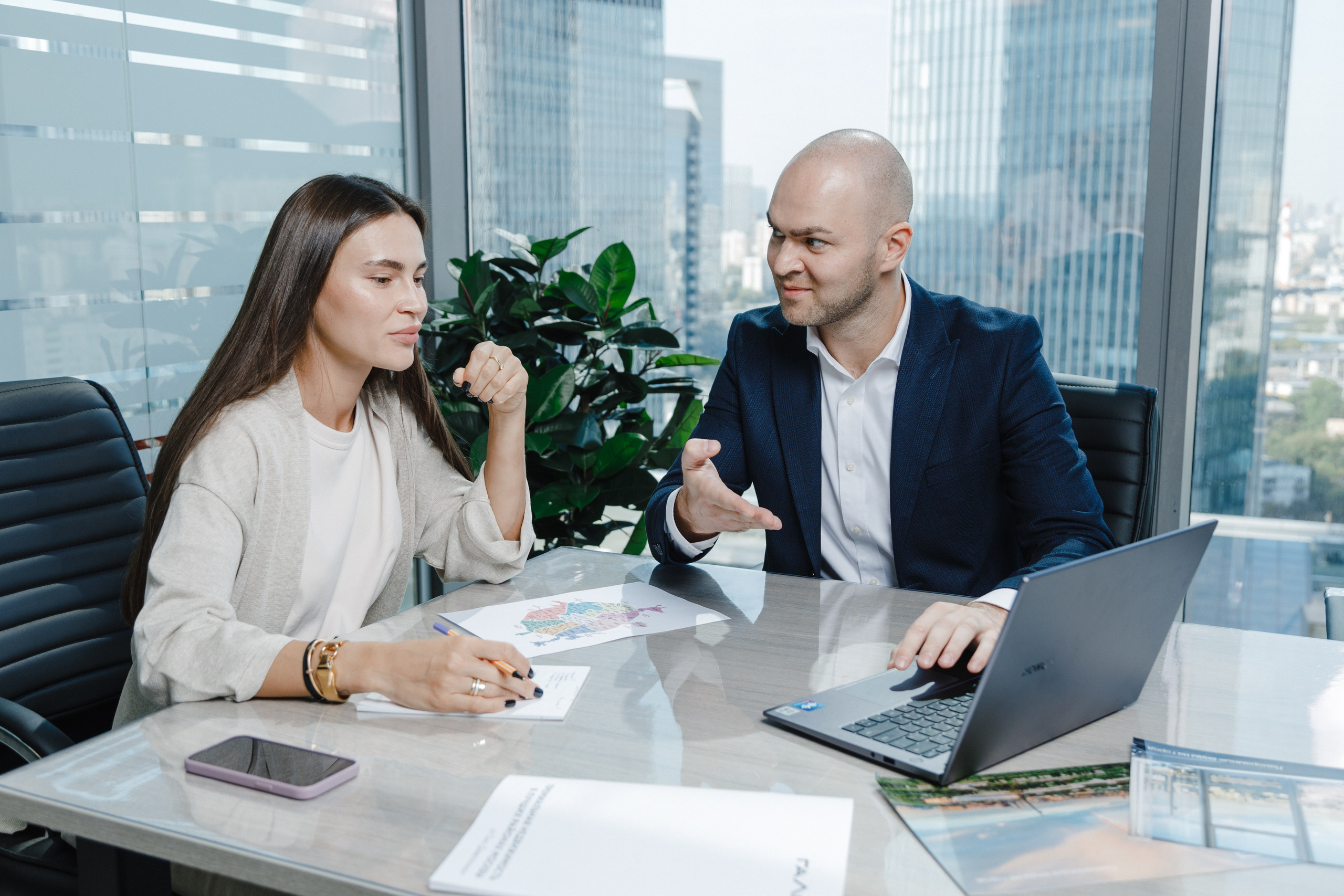 Два экономиста обсуждают проект, работая в офисе с видом на Москва-Сити.