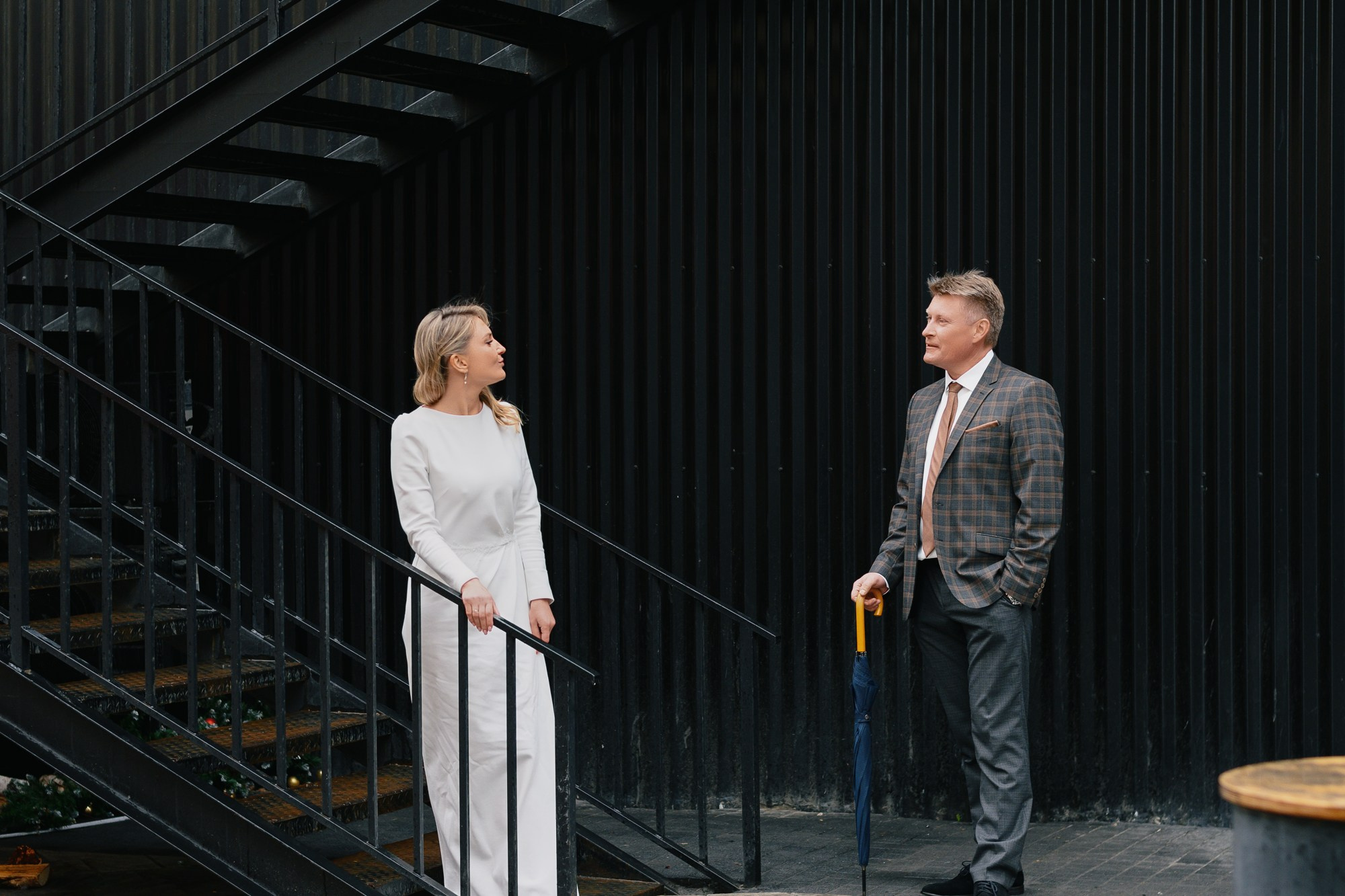 Молодожены на фоне темных графичных стен, современный стиль свадебной съемки