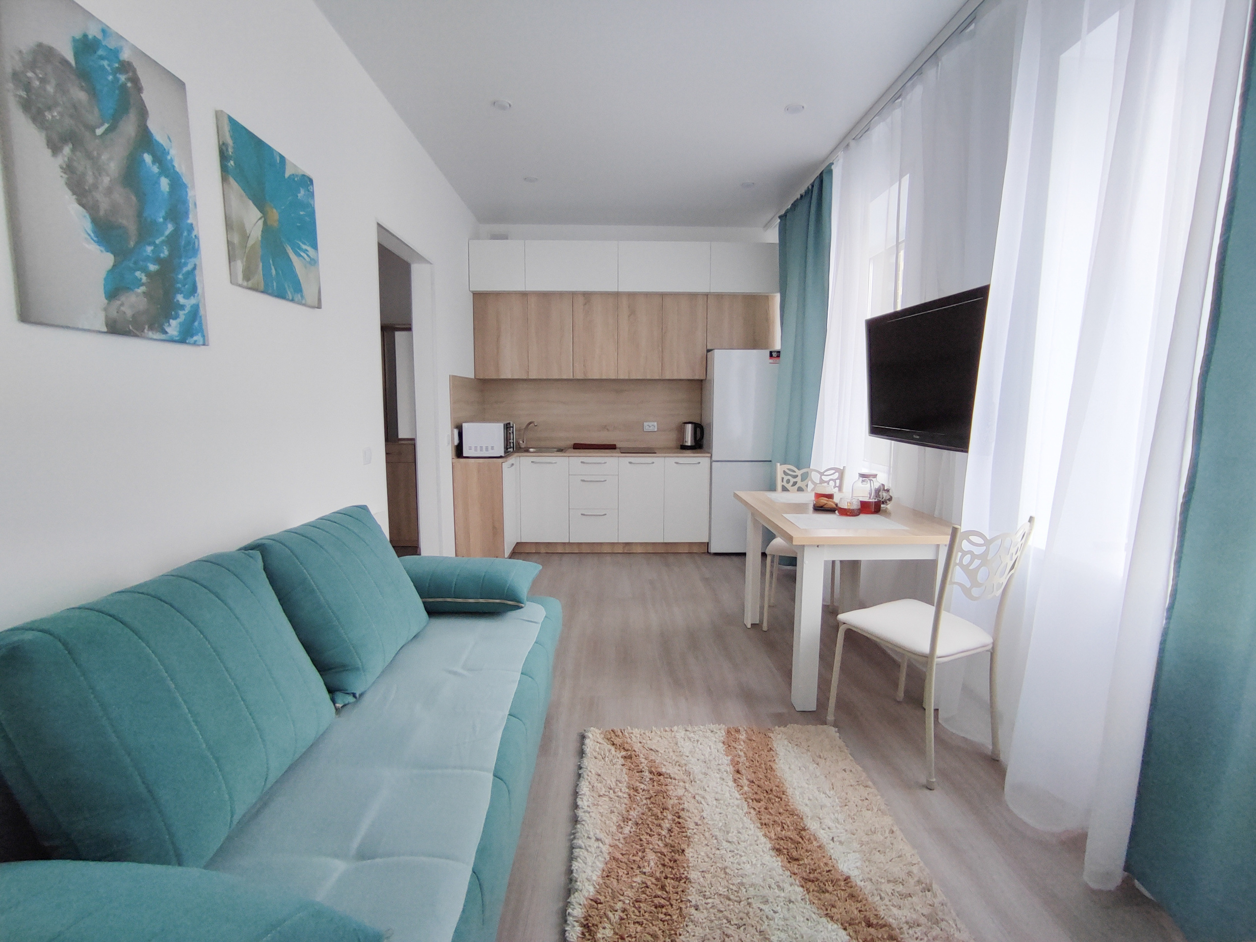 Уютная квартира с мебелью бирюзового цвета. Большие окна, кухня совмещена с залом.