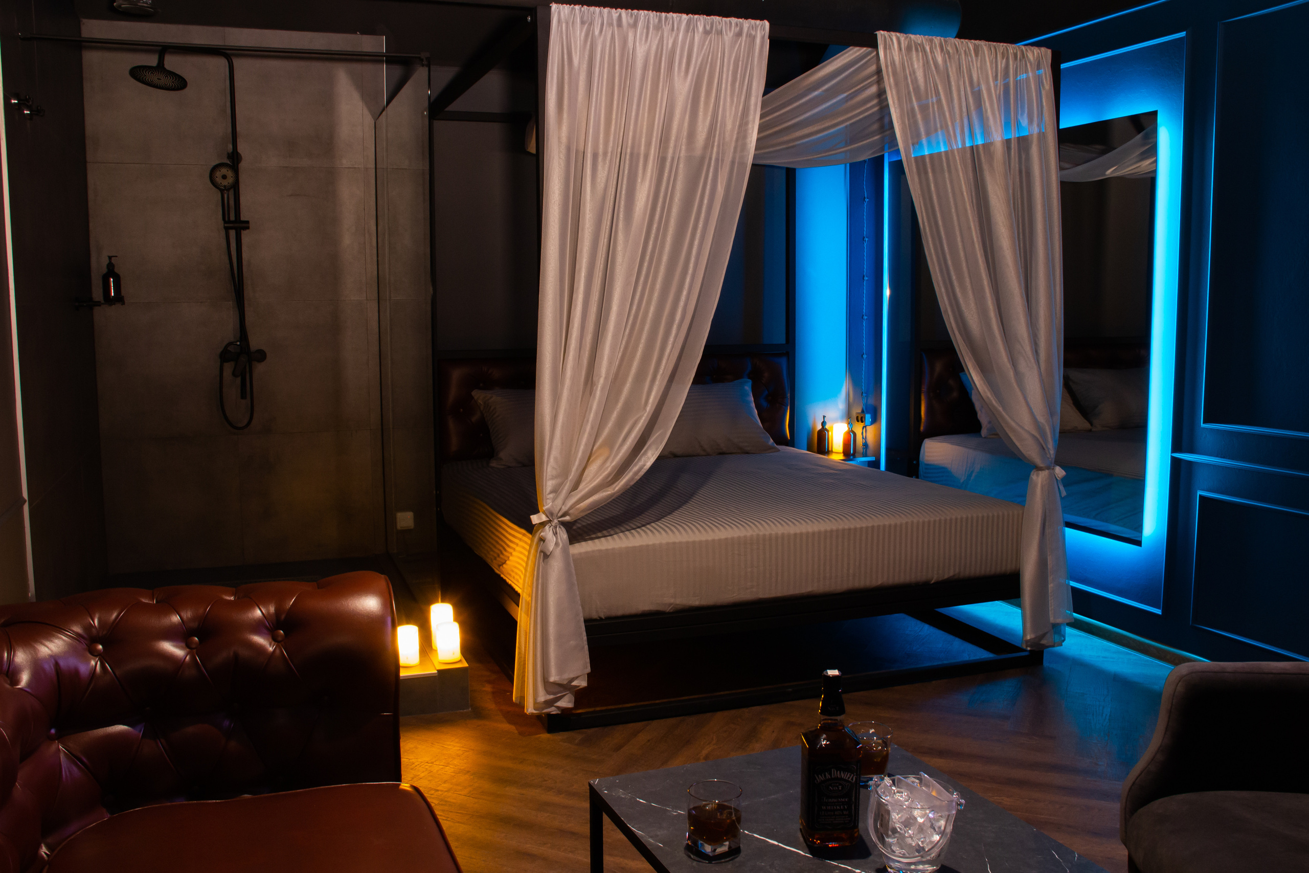 Интерьерная фотосьемка салона эротического массажа в Новосибирске. Большая кровать, большой кожаный коричневый диван, интимная обстановка.