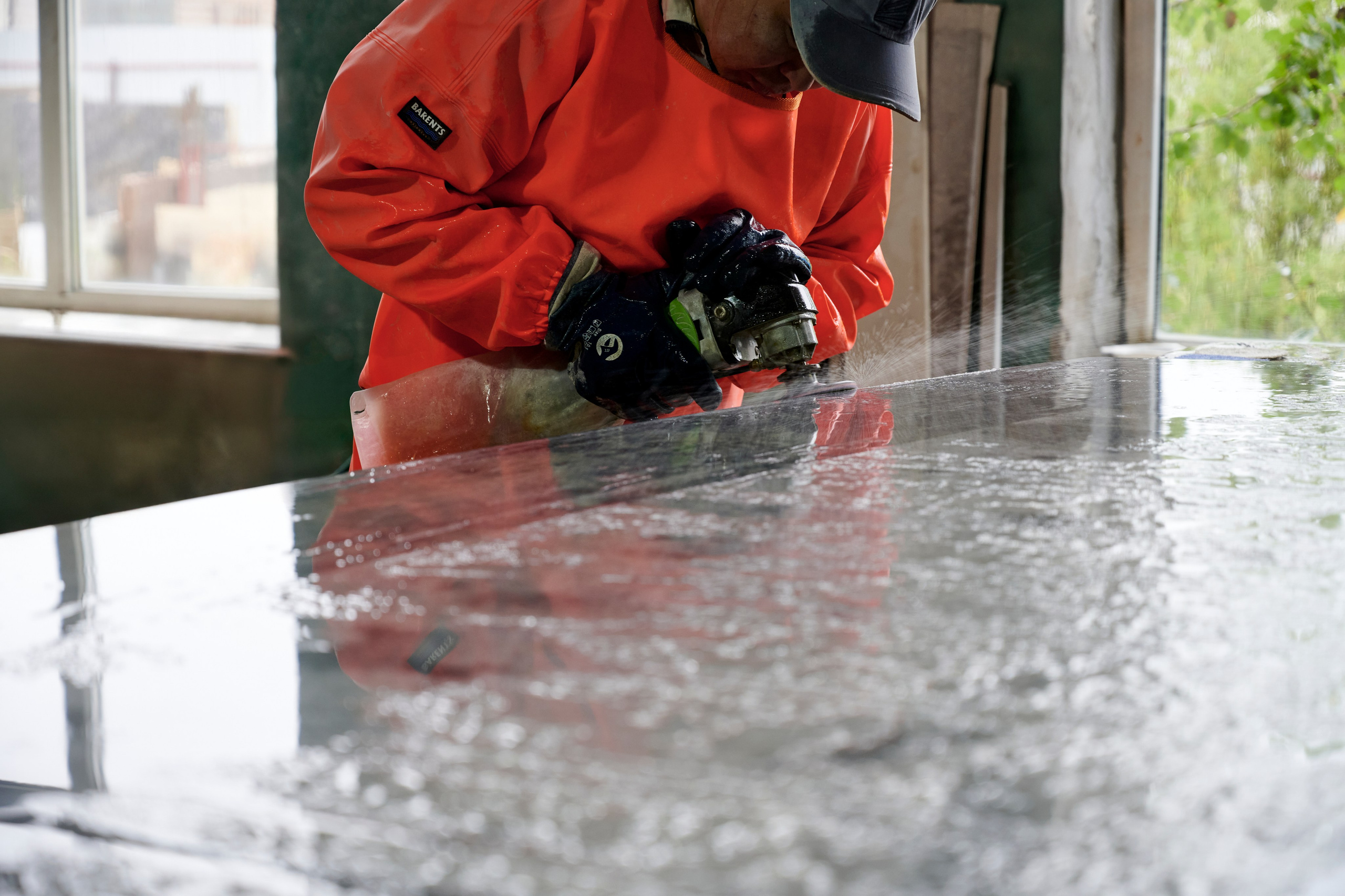 Рука в перчатке смывает воду с поверхности камня