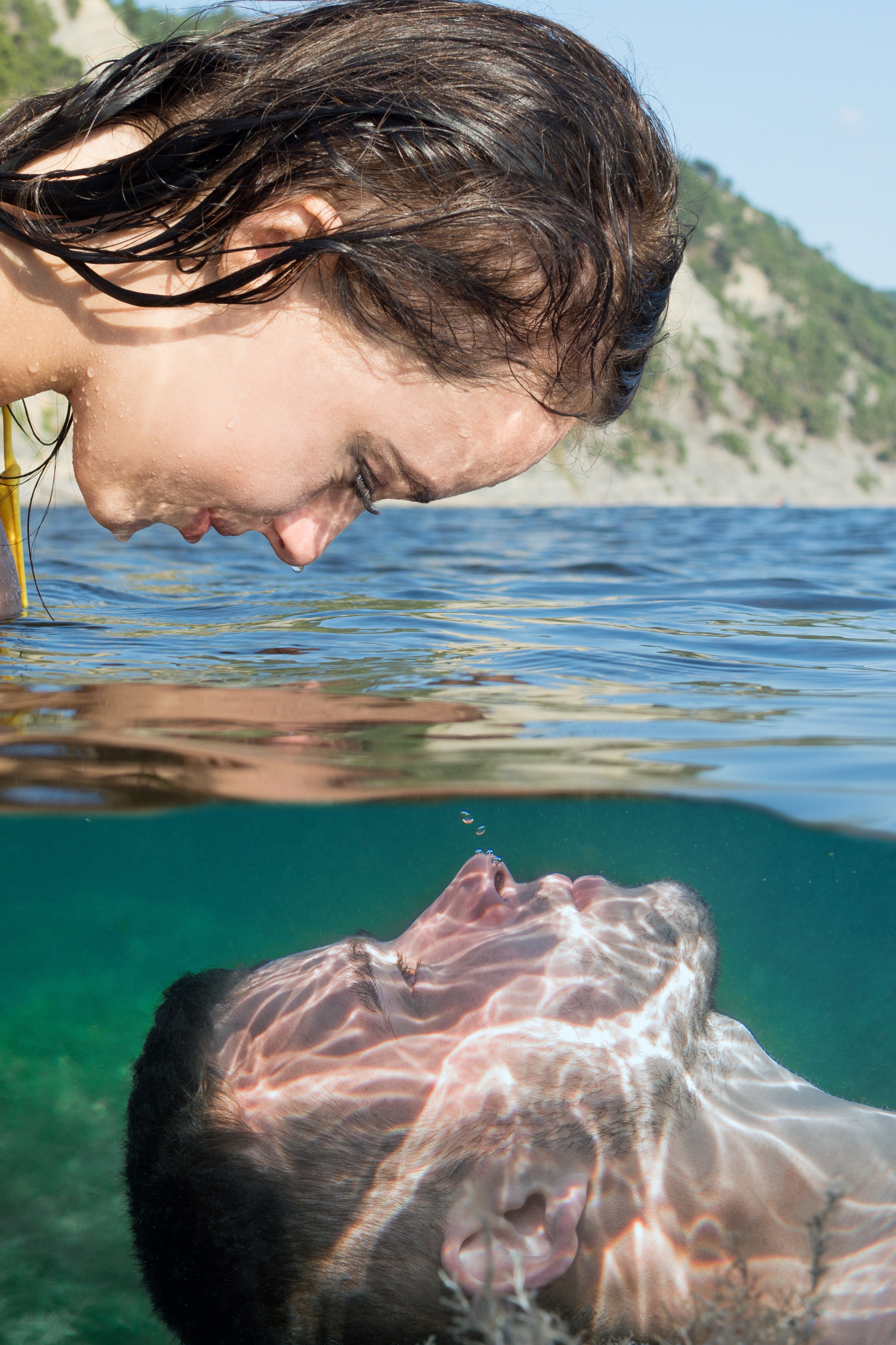 Парень под водой и девушка над водой, смотрящие друг на друга