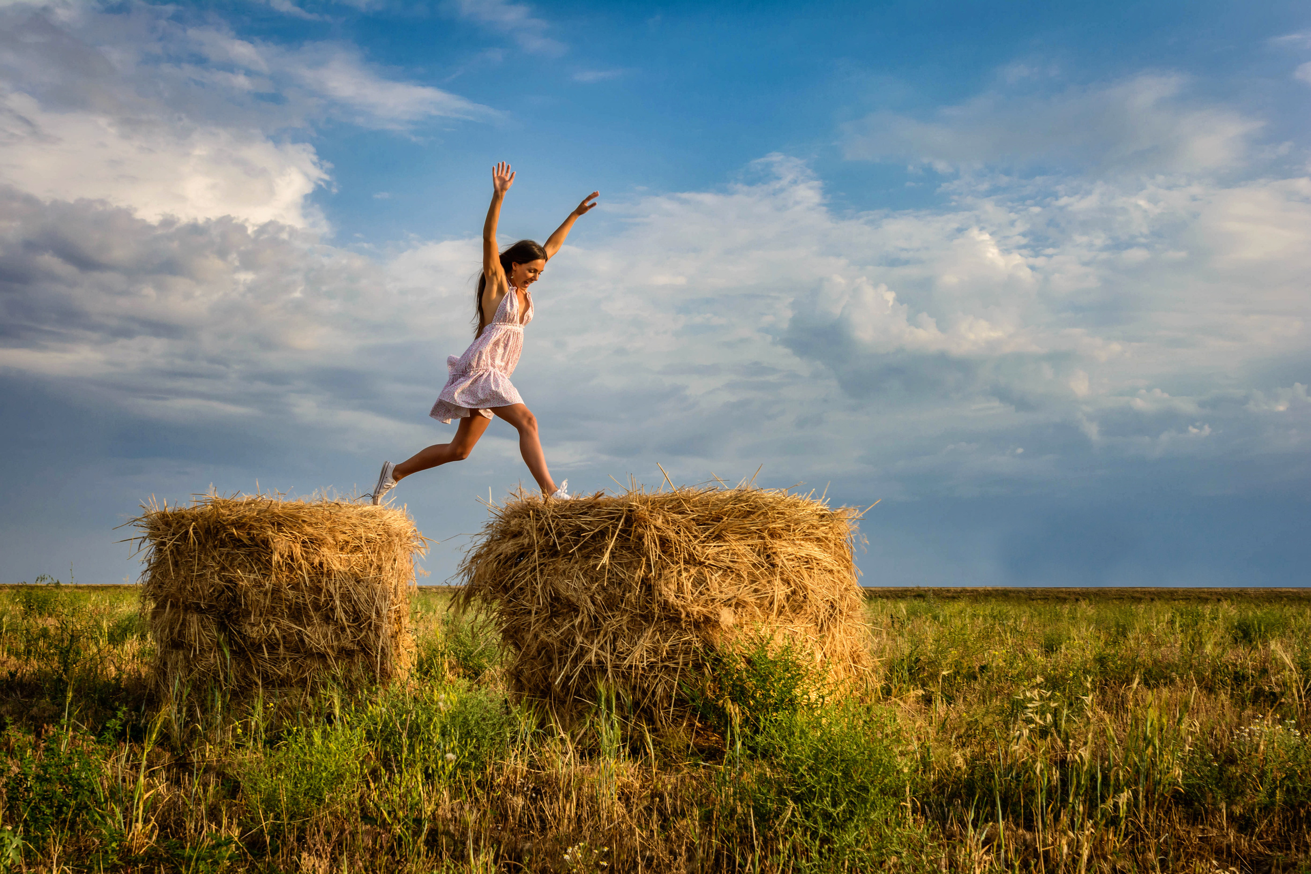 Девушка в сарафане, прыгающая на стогах