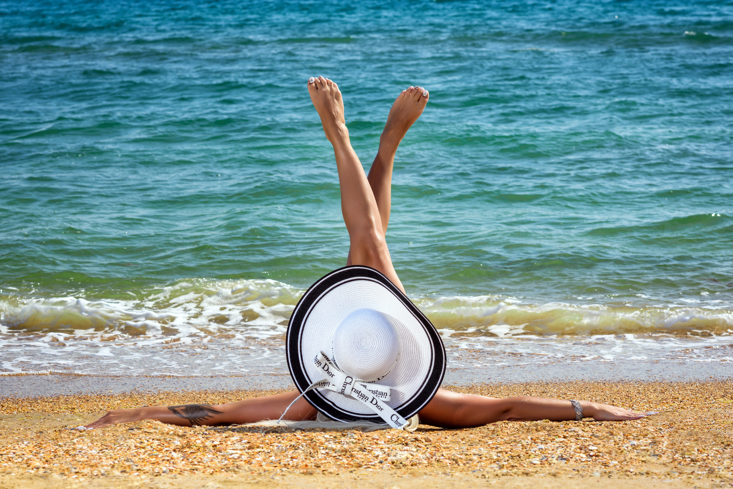 Девушка в шляпе, лежащая на берегу моря