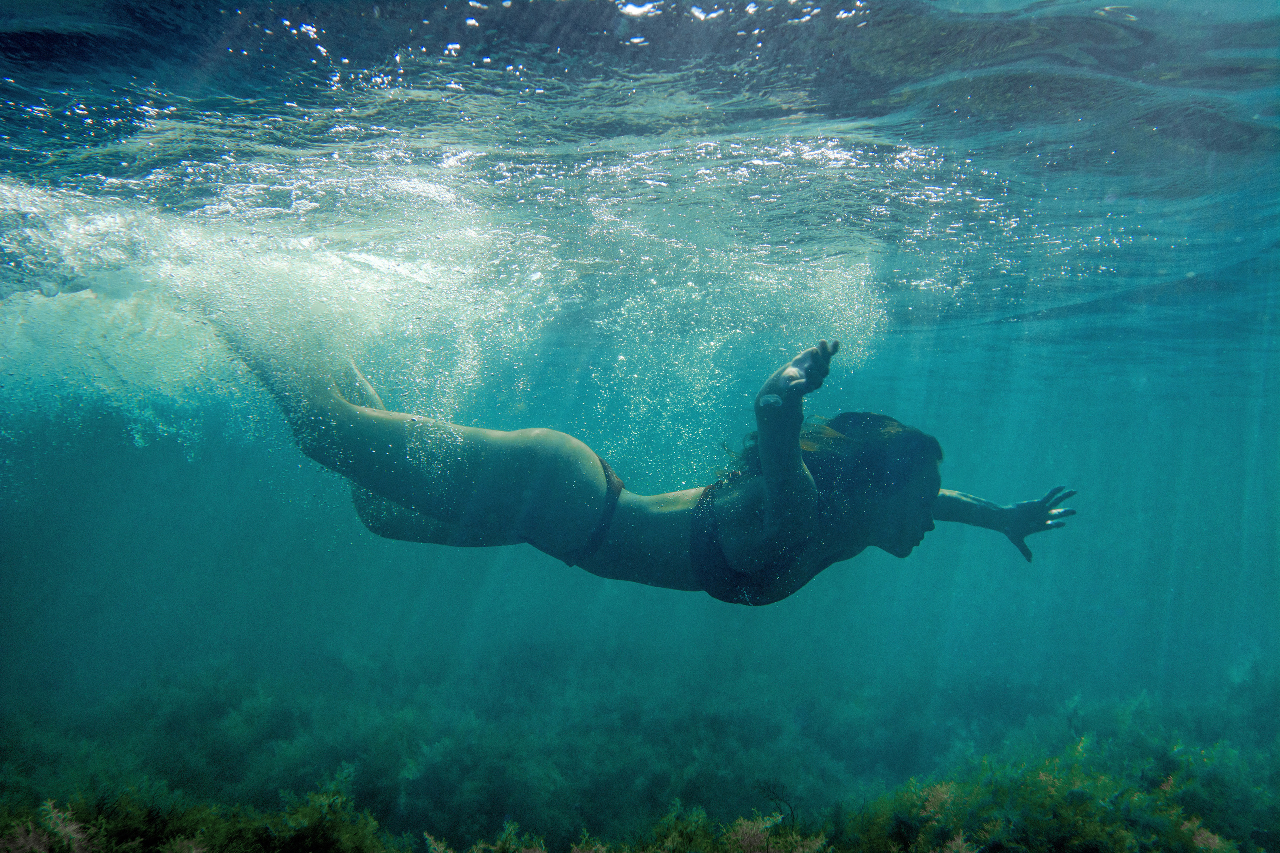 Девушка, проныривающая под водой в море