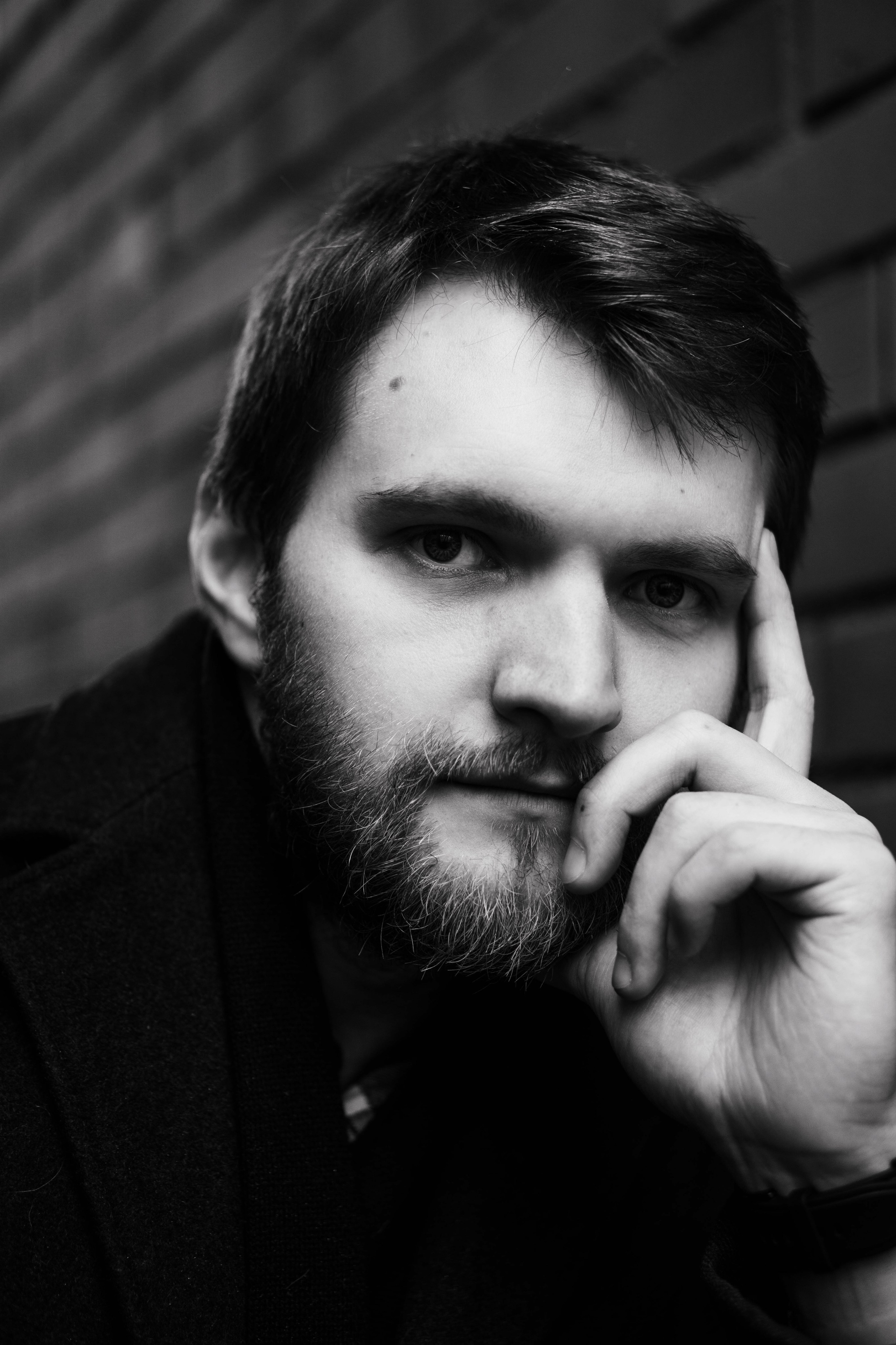 черно-белый портрет молодого мужчины с бородой в пальто 