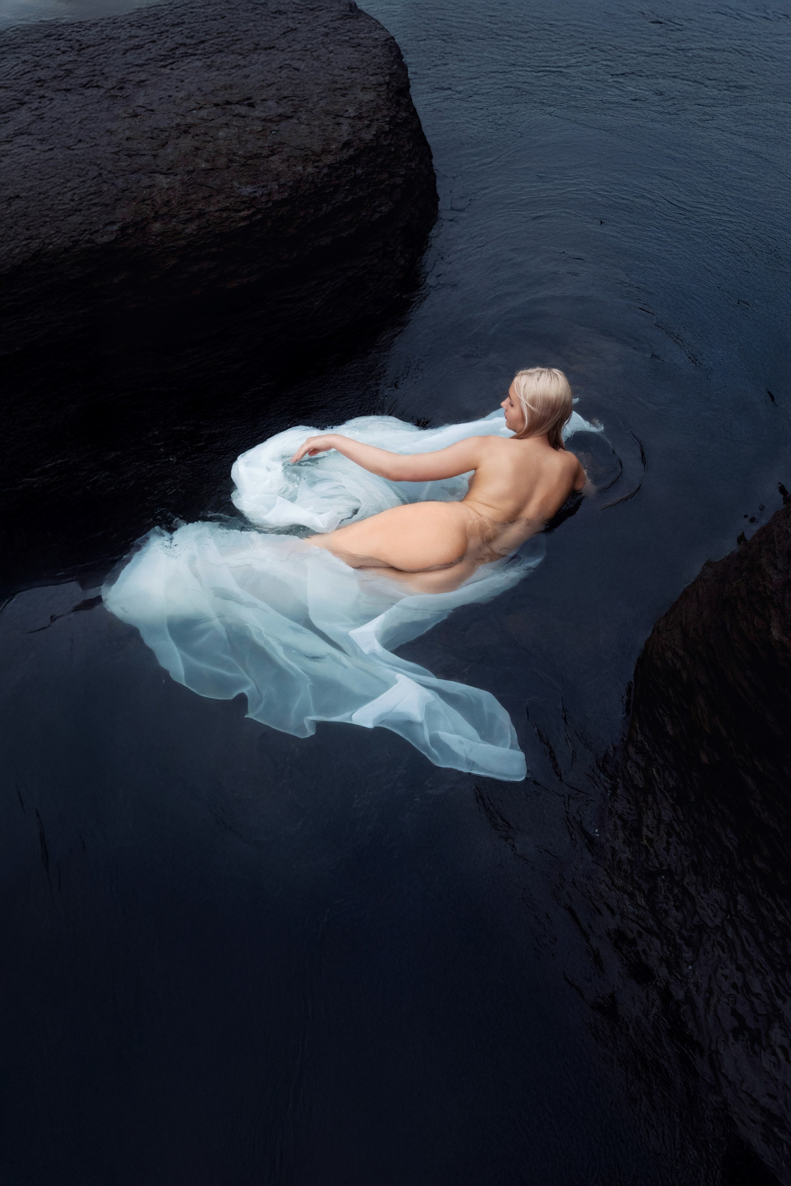 Ню фотосессия во Владивостоке. Обнаженная, голая девушка в лежит в воде, в море. С белой тканью и голой попой. Естественный цвет.