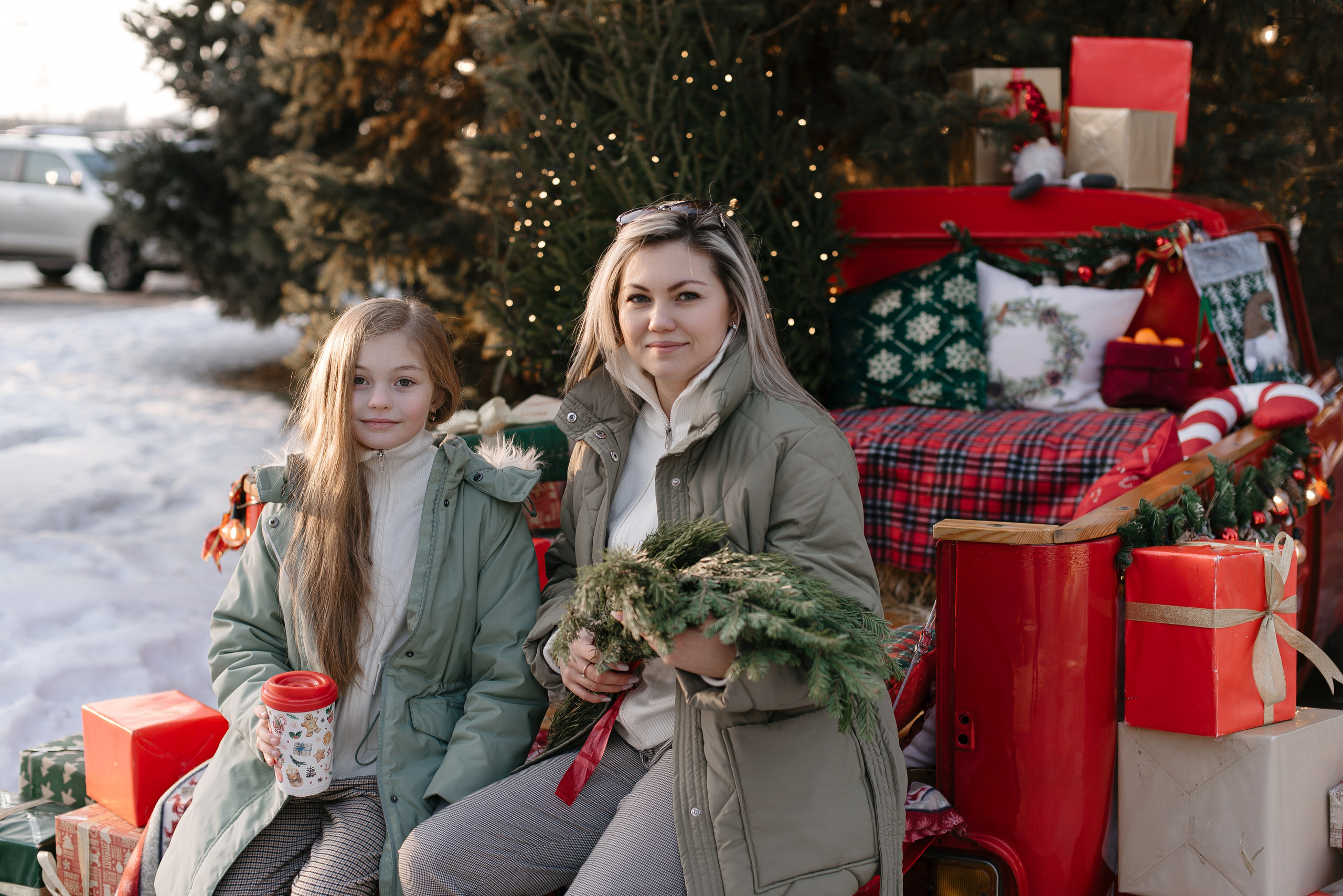 Мама и дочка в санях у новогодней елки