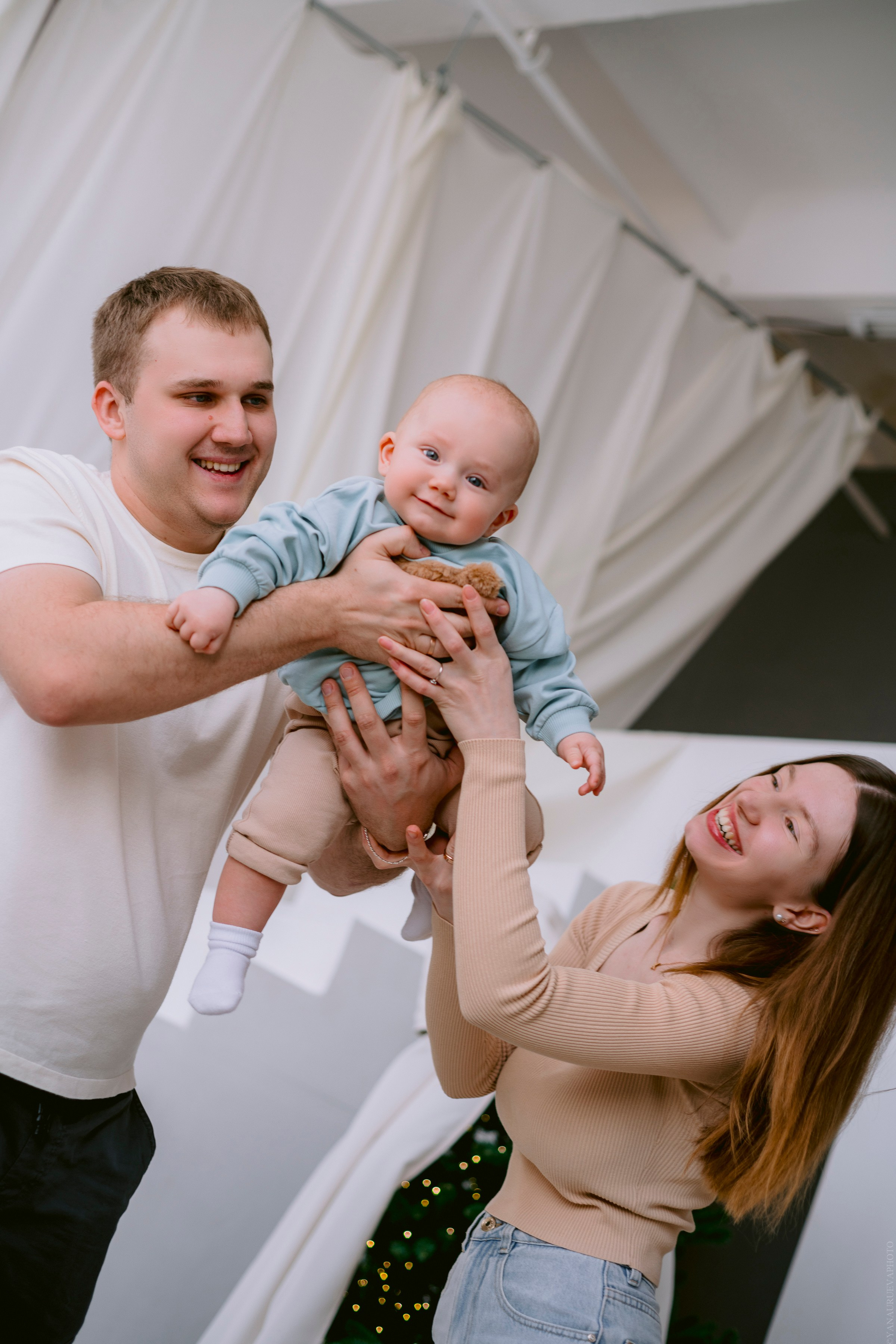 малыша держат на руках мама и папа