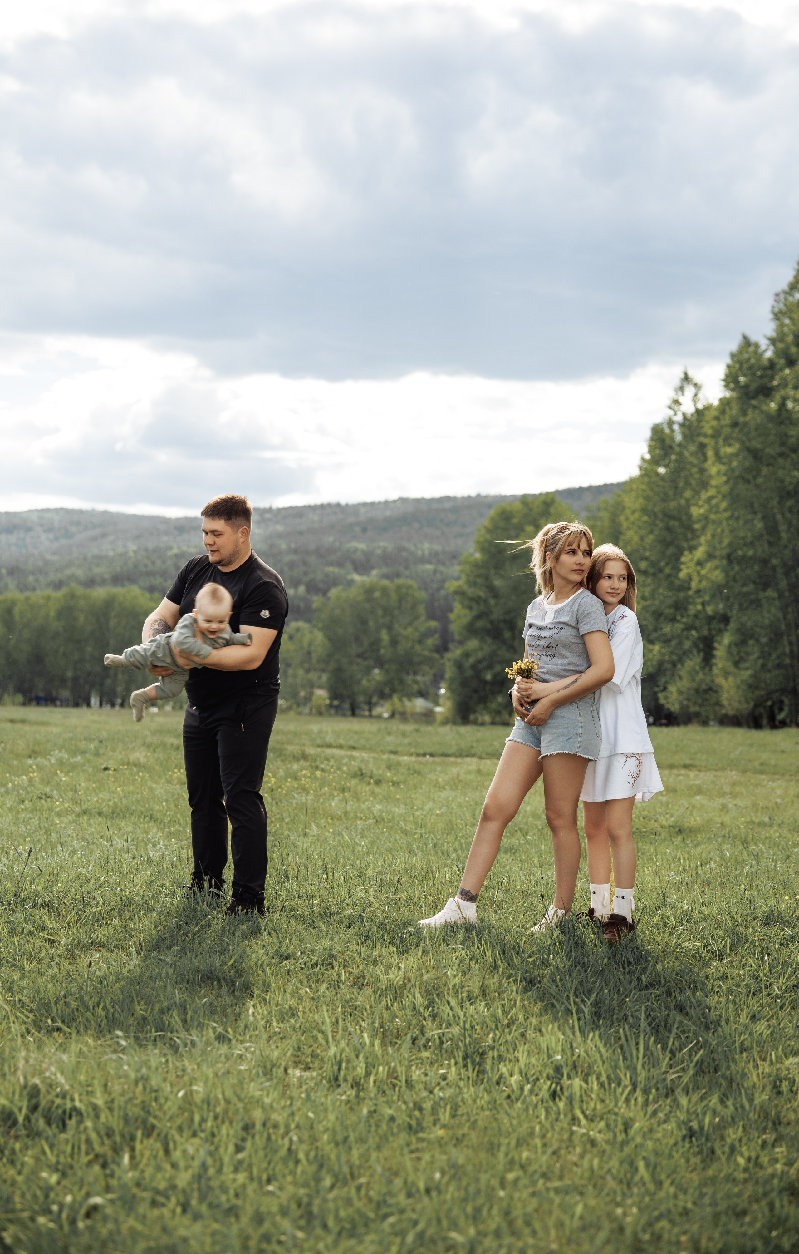 Семья с ребёнком на зелёной поляне во время фотосессии в Усть-Куте.