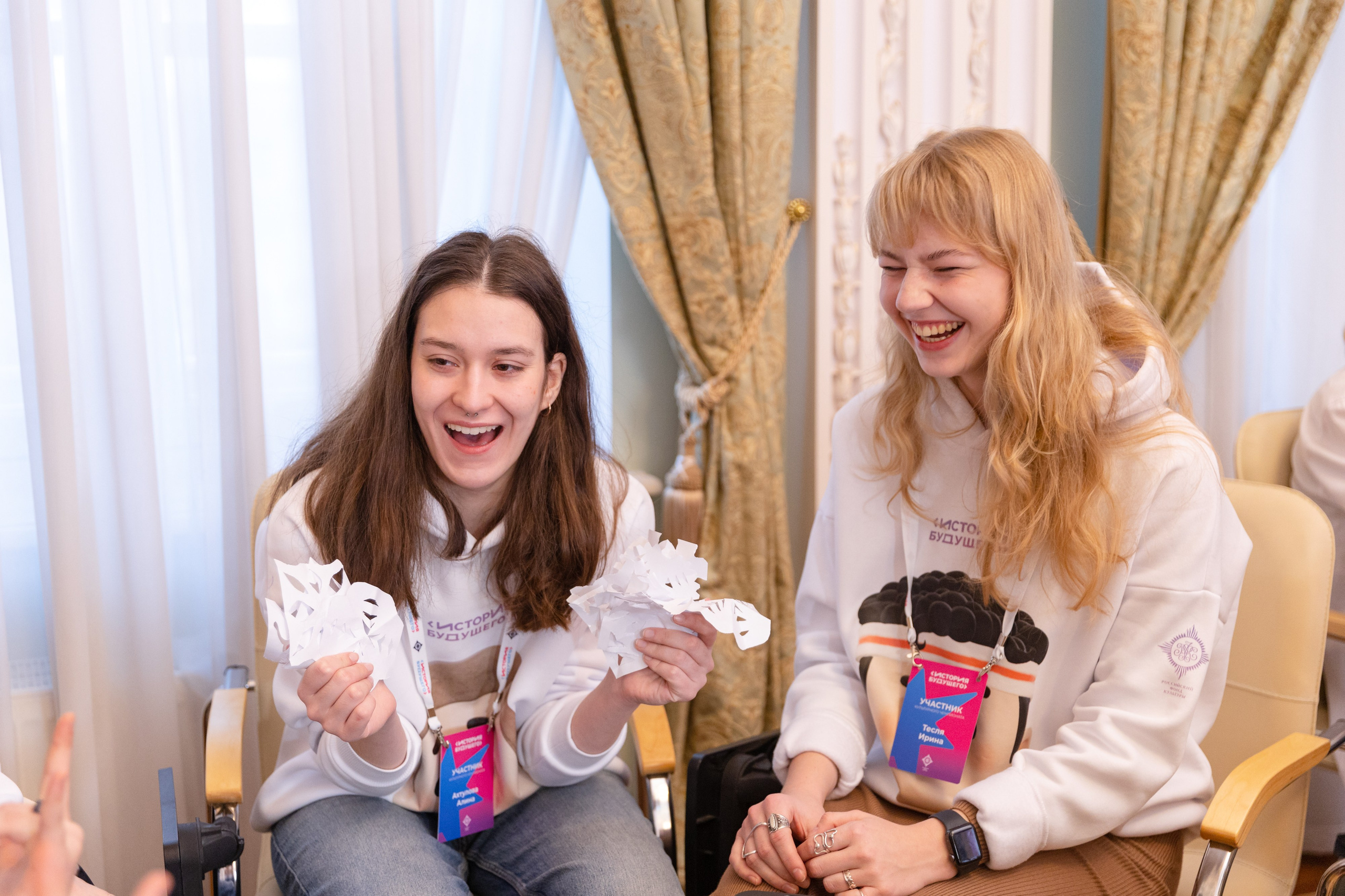 Девушка в руках держит много вырезанных снежинок.