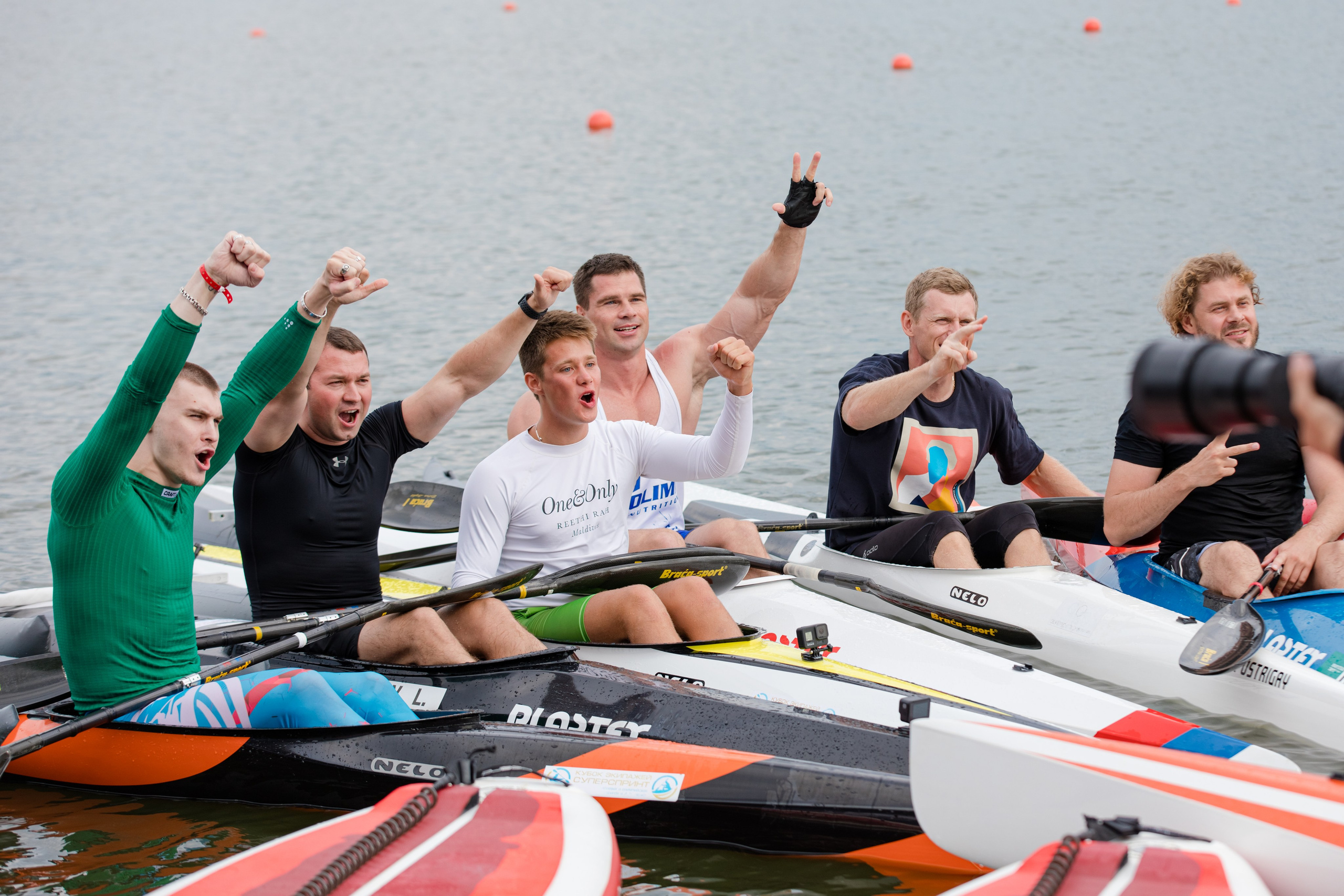 Группа спортсменов байдарочников радуются победе сидя в лодках