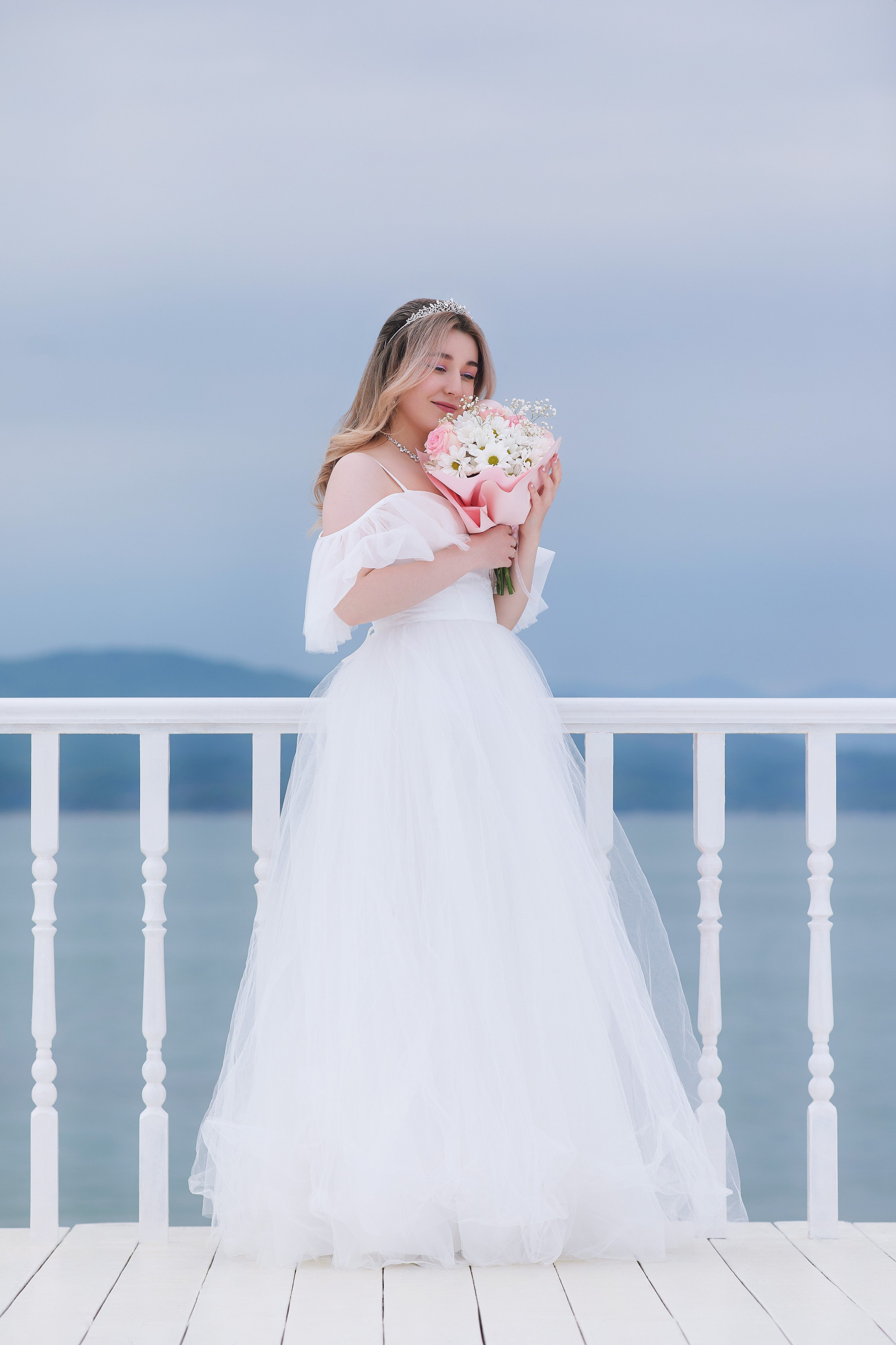 Идея для свадебной фотосессии для невесты на фоне моря и деревянного поручня
