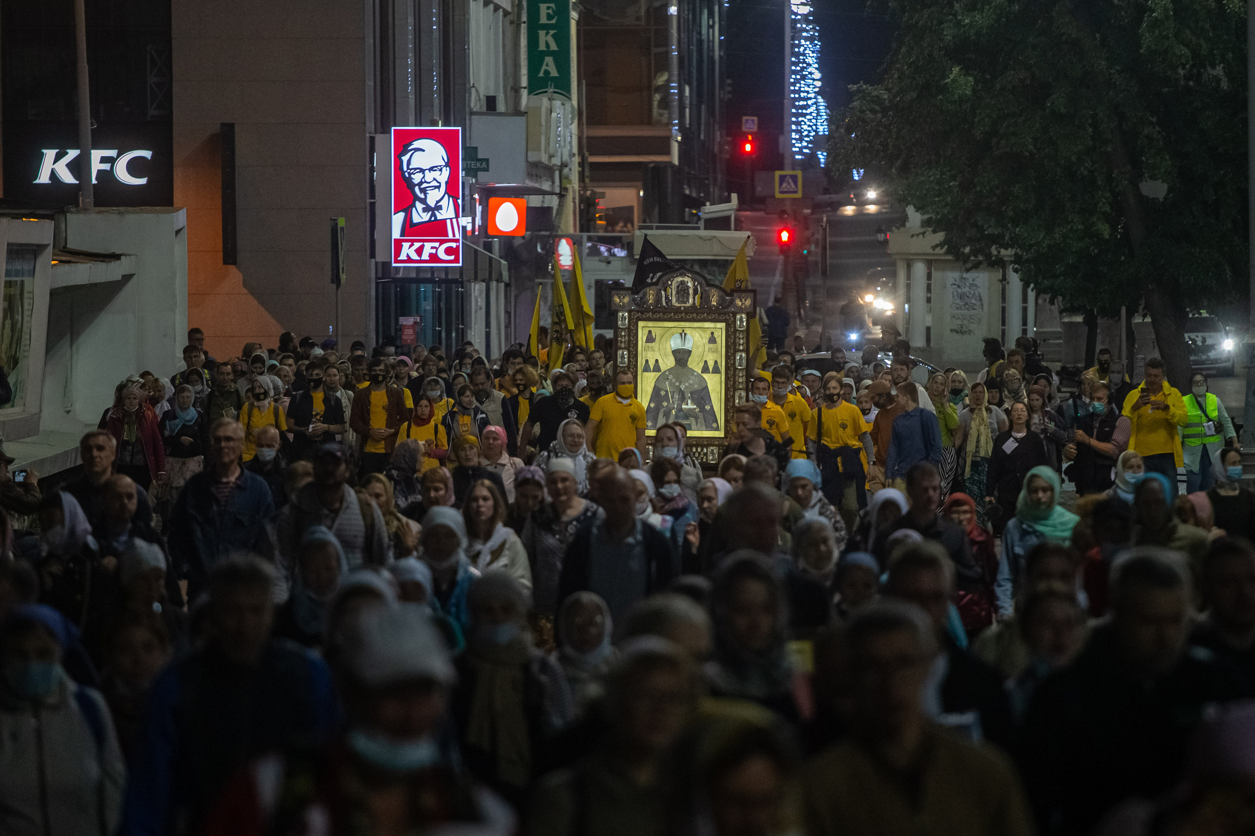 "ОСВЯЩАЯ ПУТЬ"  из серии «У каждого своя икона» Толпы паломников, держащих в руках икону, движутся по проспекту Ленина мимо ресторана KFC в сторону Ганиной ямы. Екатеринбург, 2022