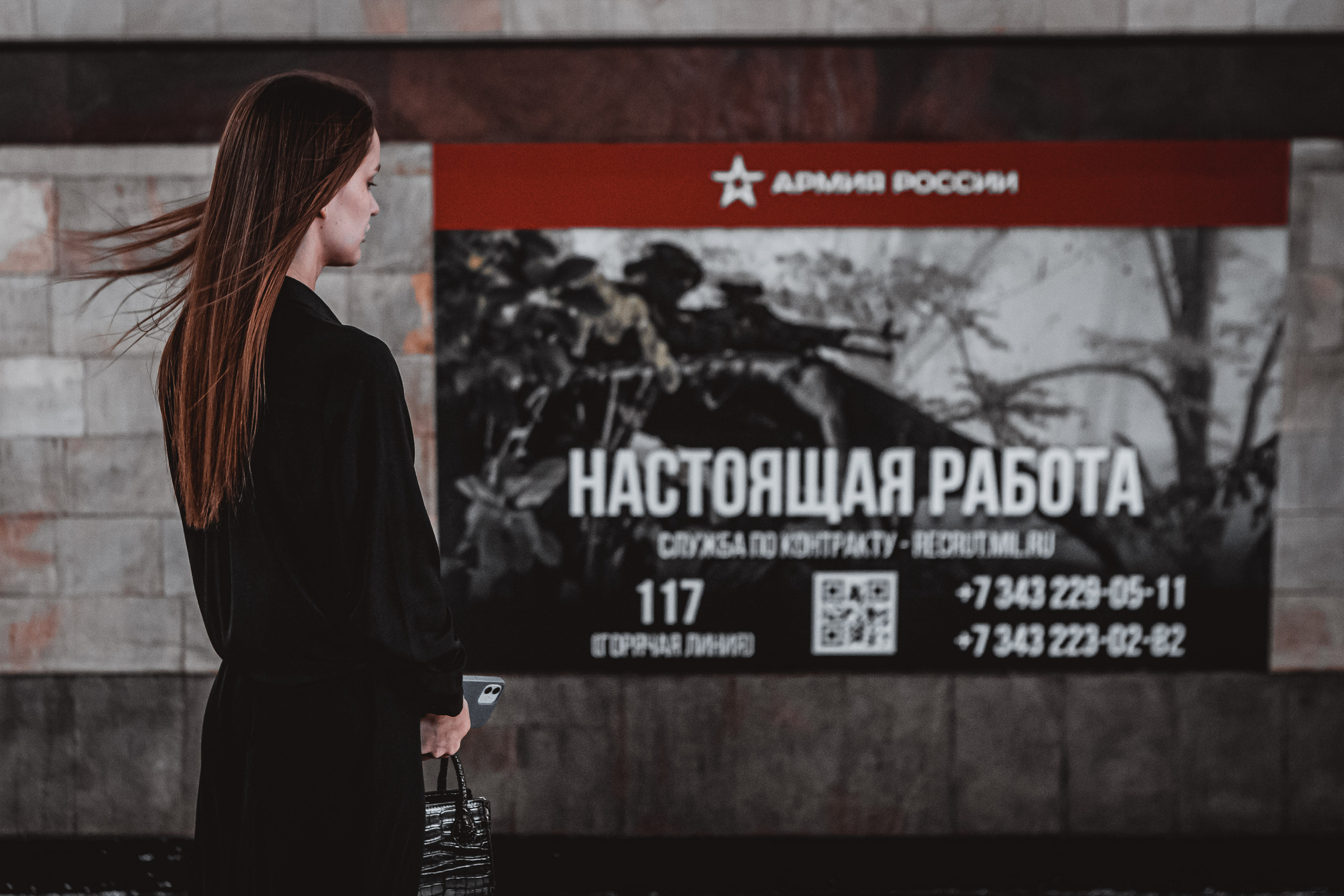 "НАСТОЯЩАЯ РАБОТА из серии «Новая реальность 2022» Одиноко стоящая девушка на платформе метро в период агитационной кампании по набору добровольцев в ряды армии РФ.  Екатеринбург, 2023