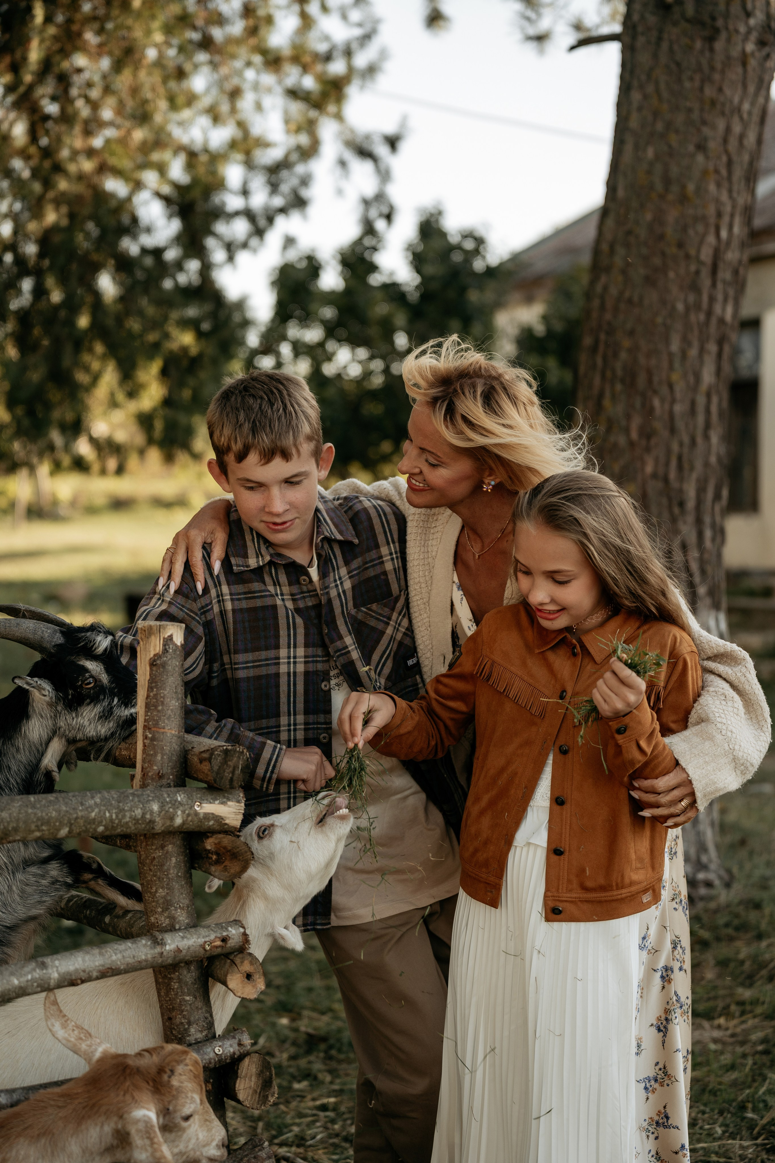 Семейная фотосессия в Анапе на эко-ферме: мама с детьми радостно кормят дружелюбных коз. Фотограф Анапа.