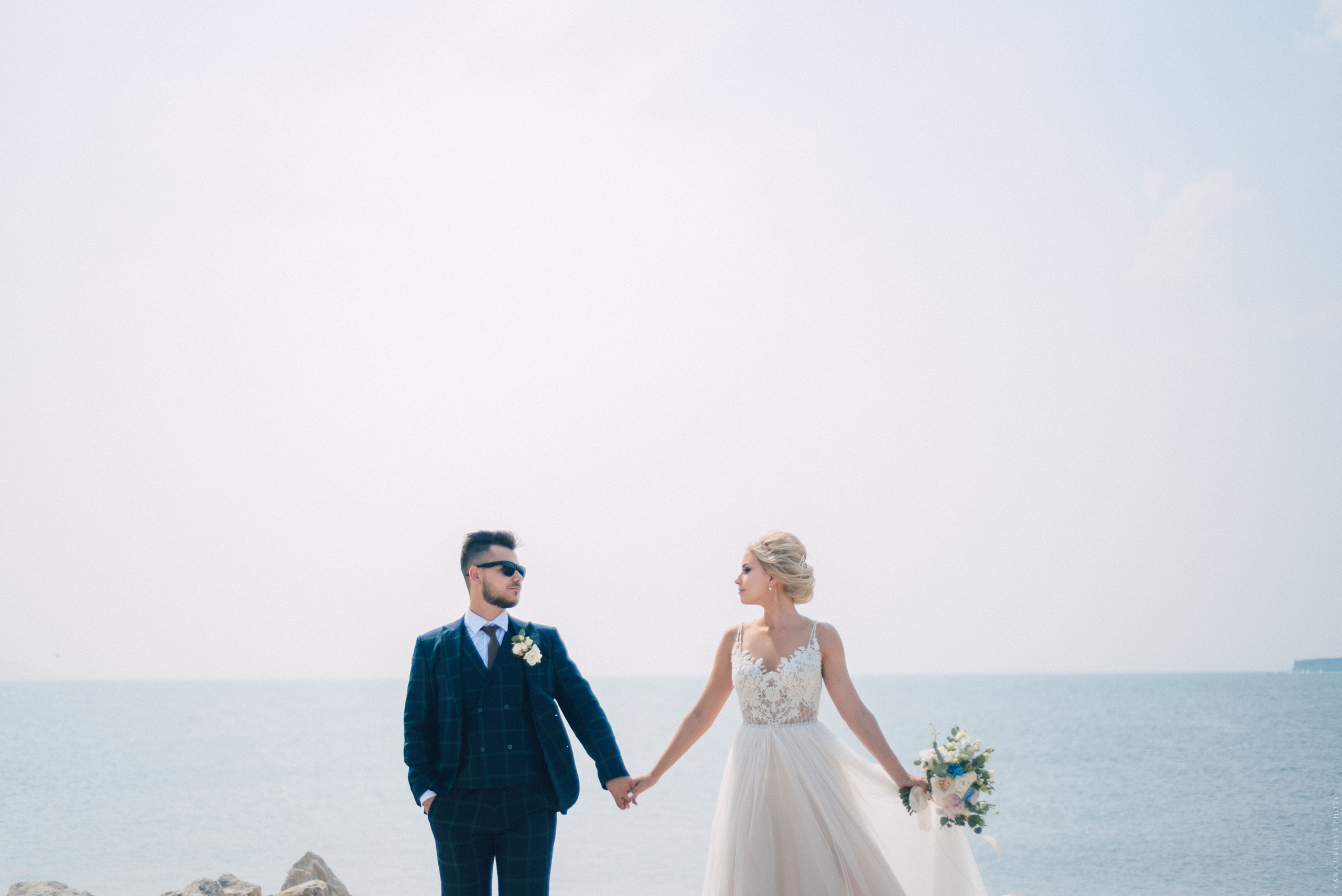 Молодожены держатся за руки на фоне реки