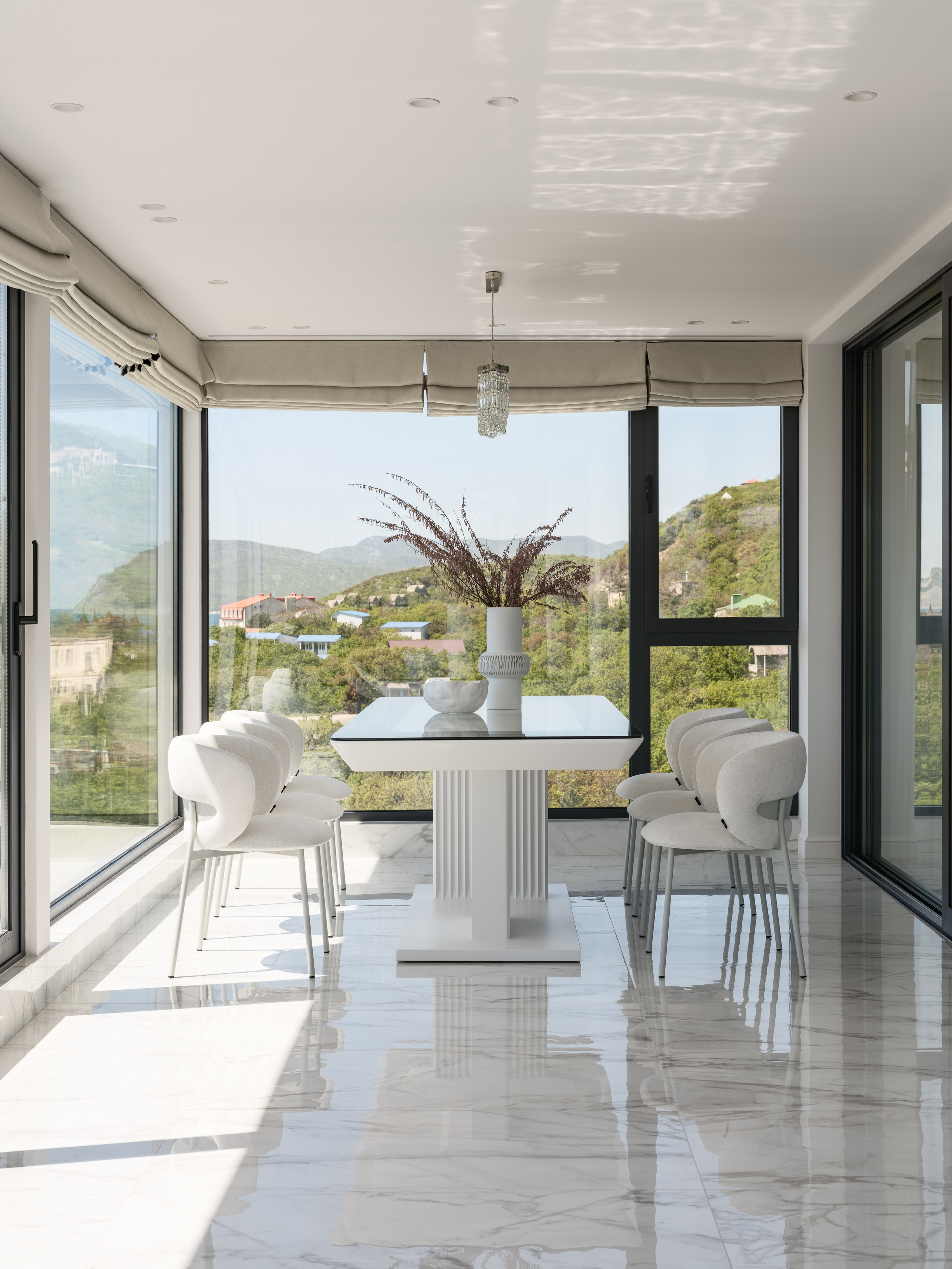 Современная столовая с панорамными окнами, белыми стульями и композицией в вазе на стеклянном столе — изысканный интерьер с видом на природу, разработанный дизайнером Алёной Боярской, стилистика Натальи Якушевой, фотография Сергея Денисенко.