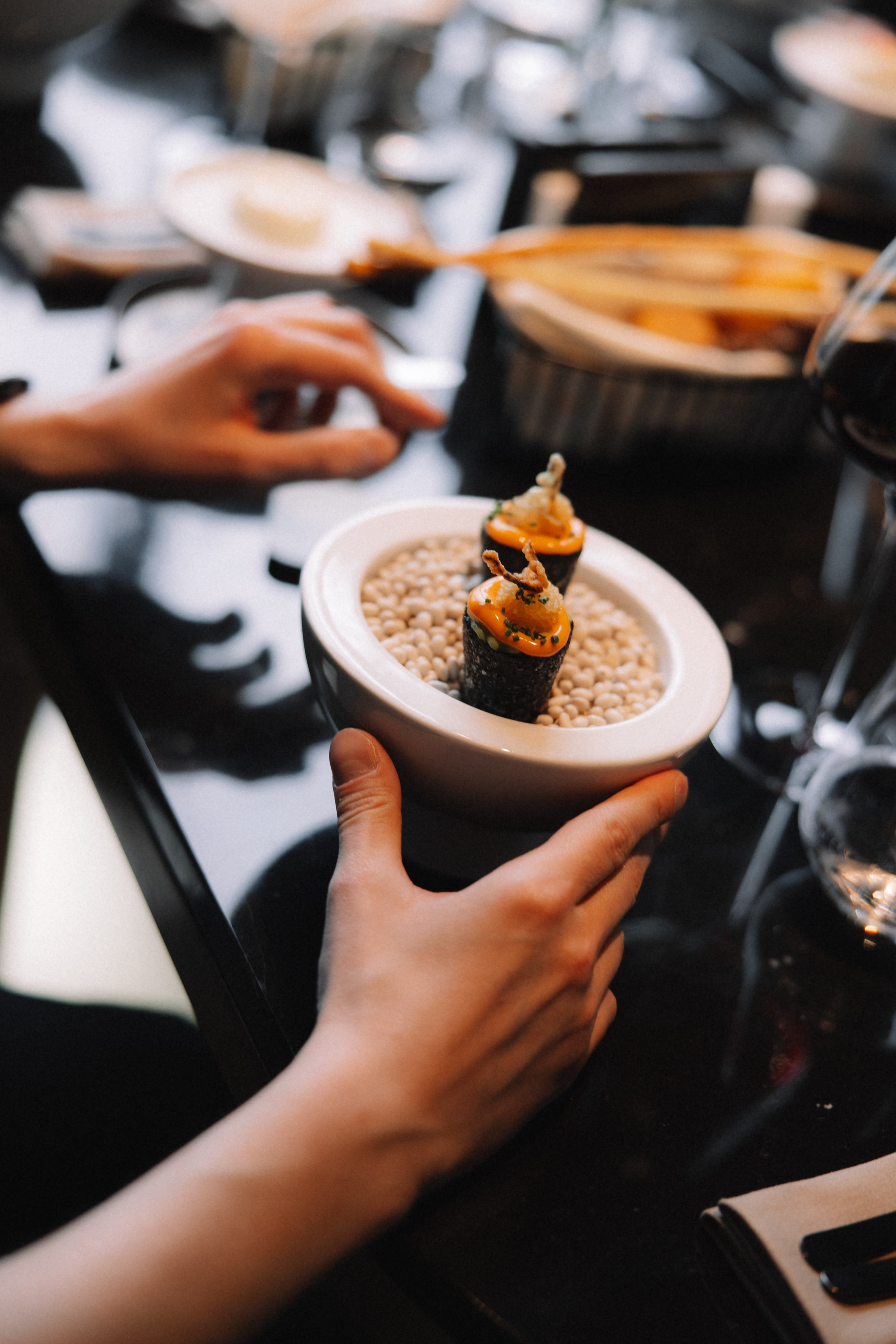 Процесс: Официант аккуратно подает закуску гостю за столом, акцент на руки и подачу.