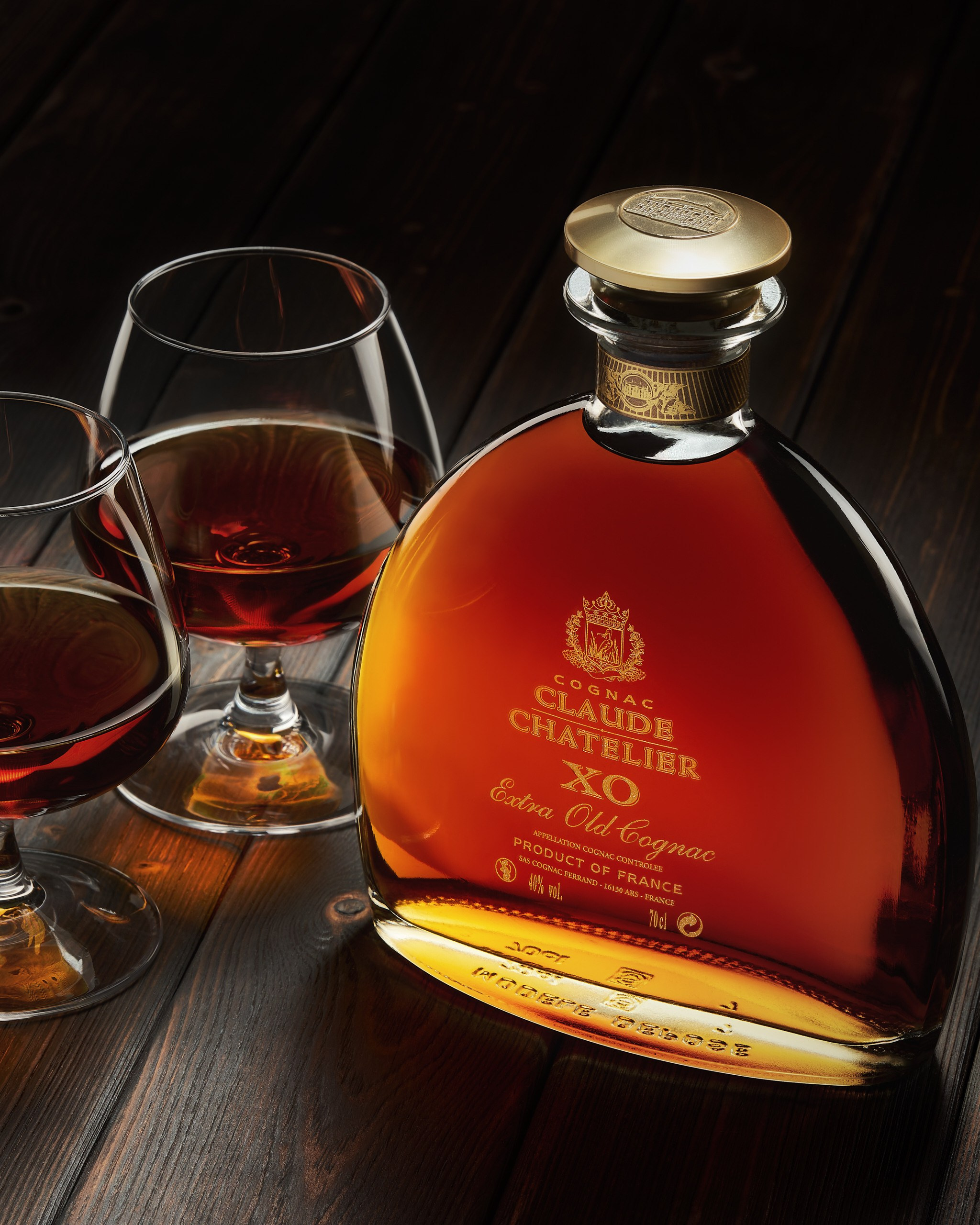 Коньяк «Claude Chatelier XO» и бокалы на тёмной деревянной поверхности