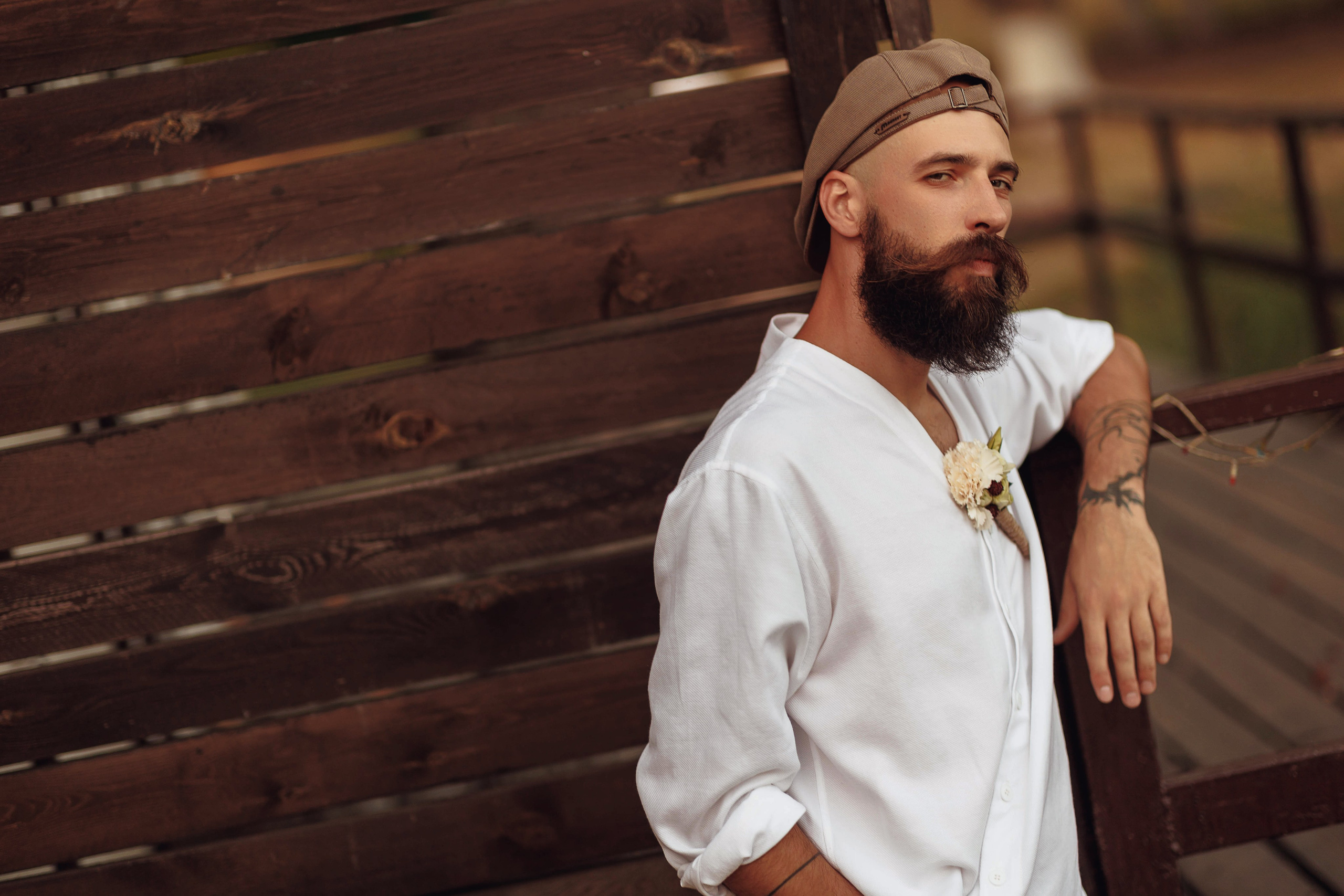 Жених облокотился на забор во время свадебной фотосессии