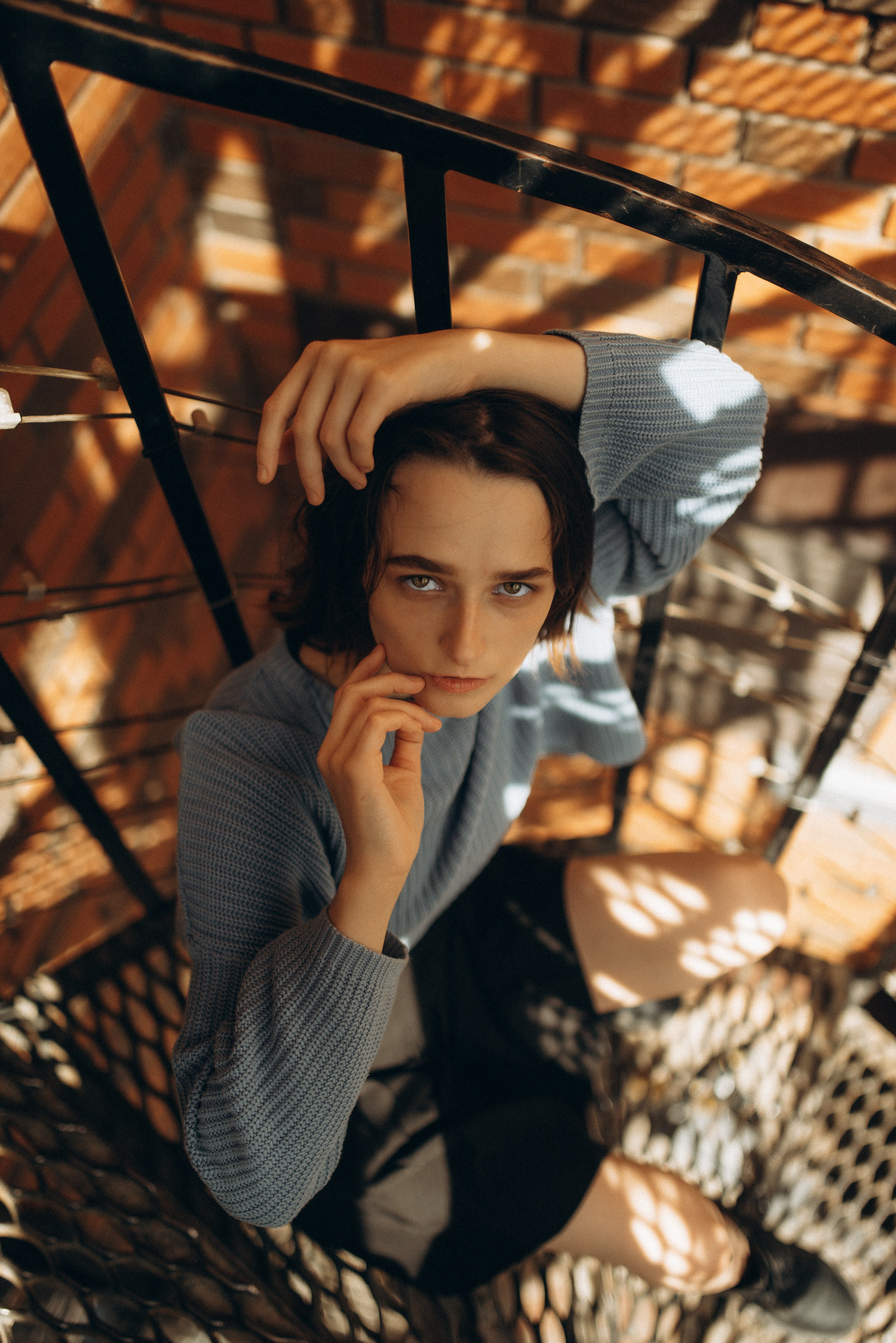 Девушка в голубом свитере на фоне кирпичной стены и черной винтовой лестницы, портретная фотосессия в индустриальном стиле. Фотосессия в Новосибирске. 4.