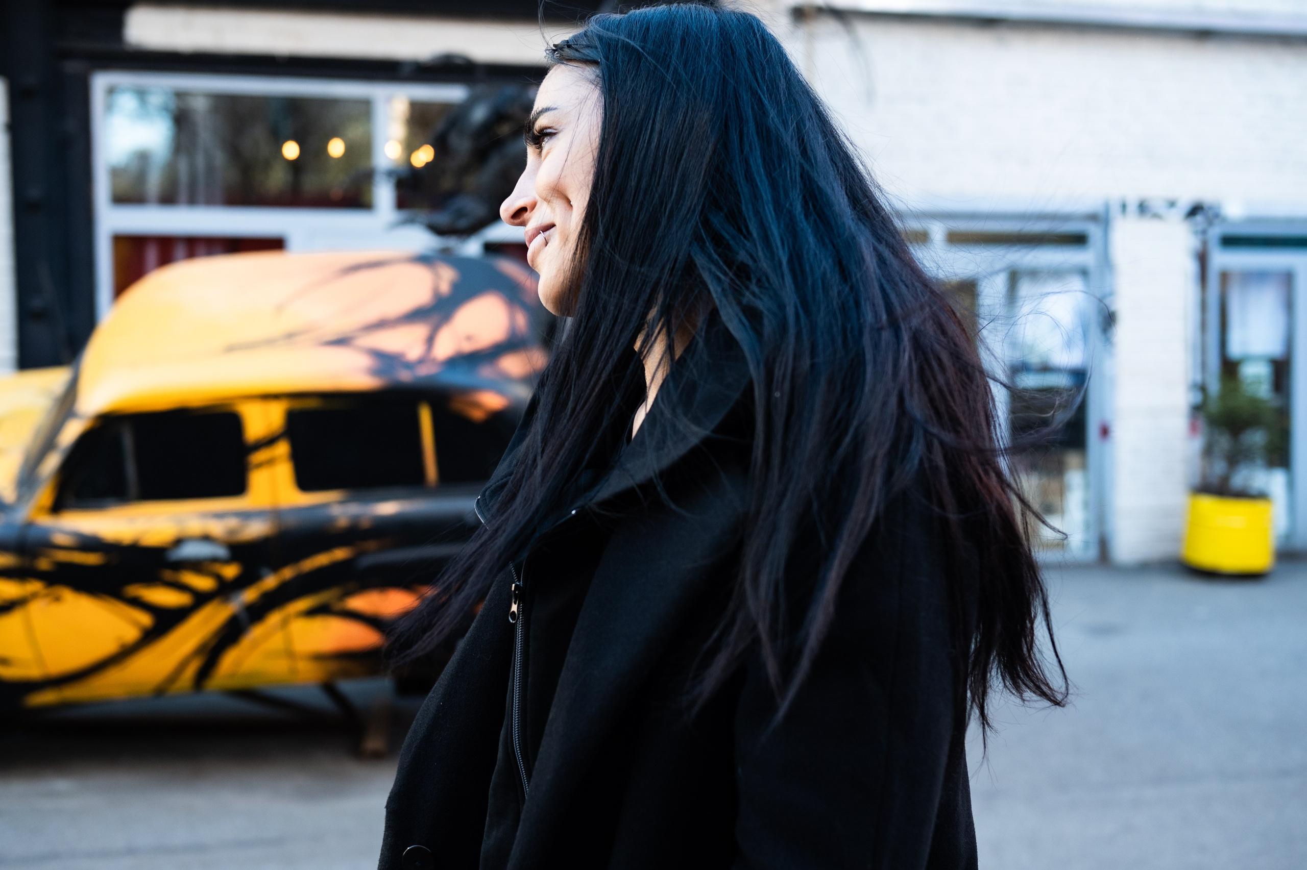 Портрет девушки с черными волосами напротив желтой машины