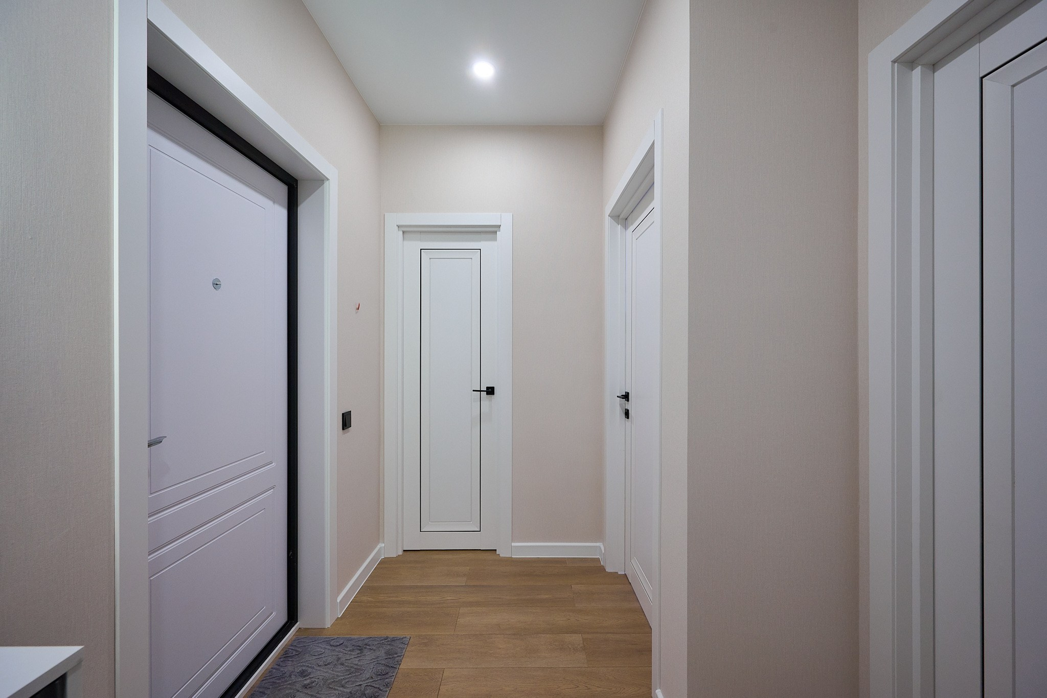 коридор с белыми дверями белой входной дверью светлым ламинатом и холодным светом