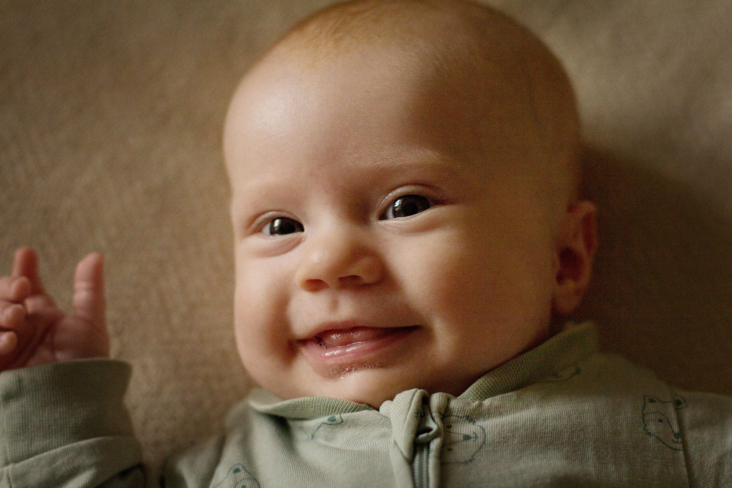 Портрет улыбающейся девочки младенца в зелёной кофточке крупным планом