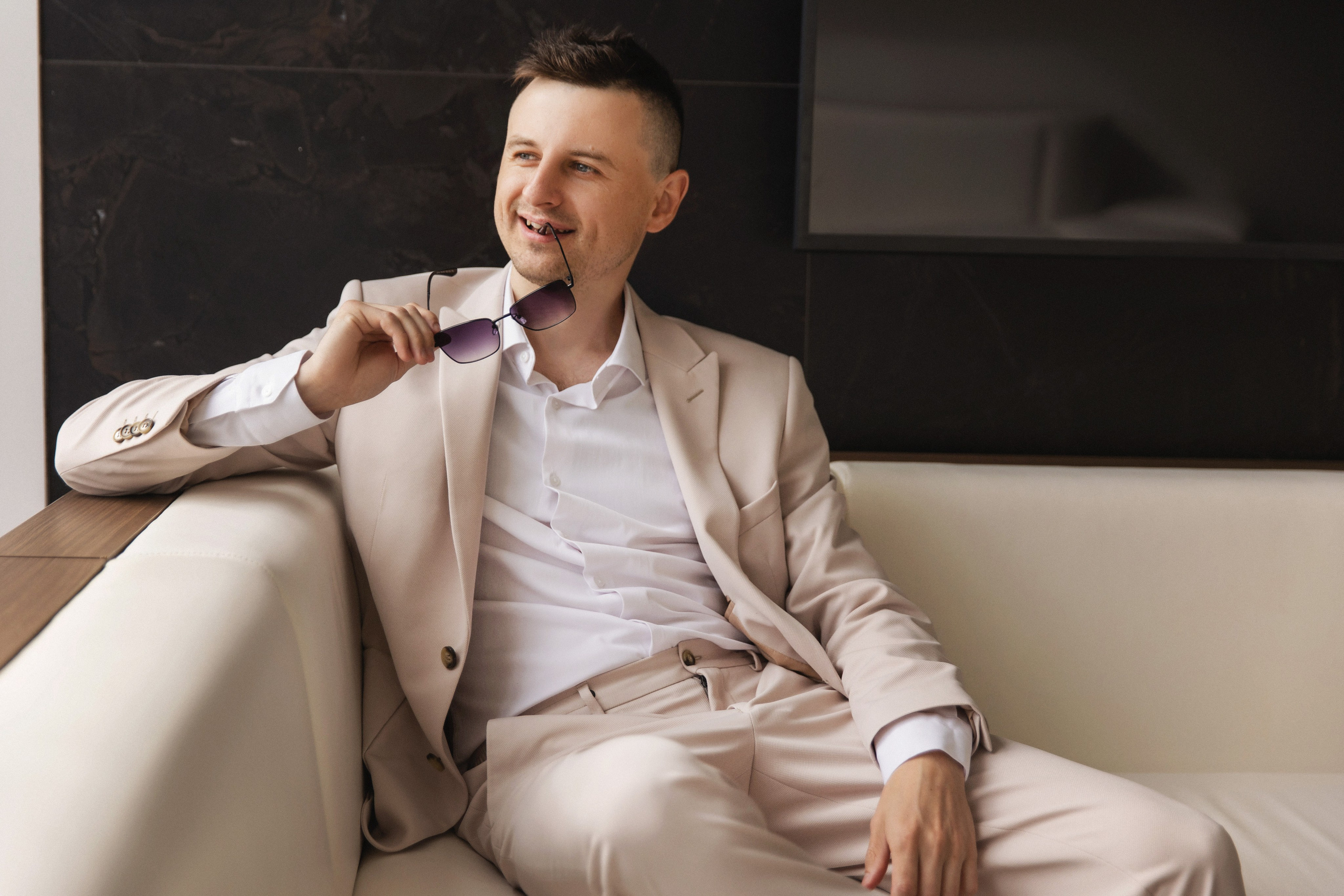 Жених прикусил дужку очков сидя на диване