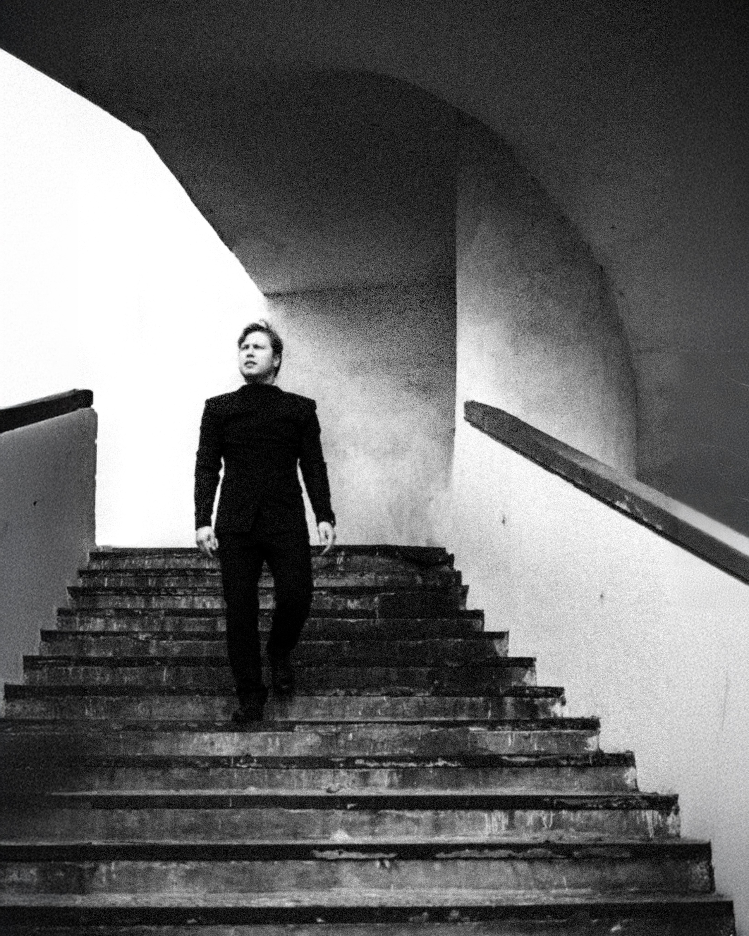 Молодой человек спускается по лестнице в ч/б