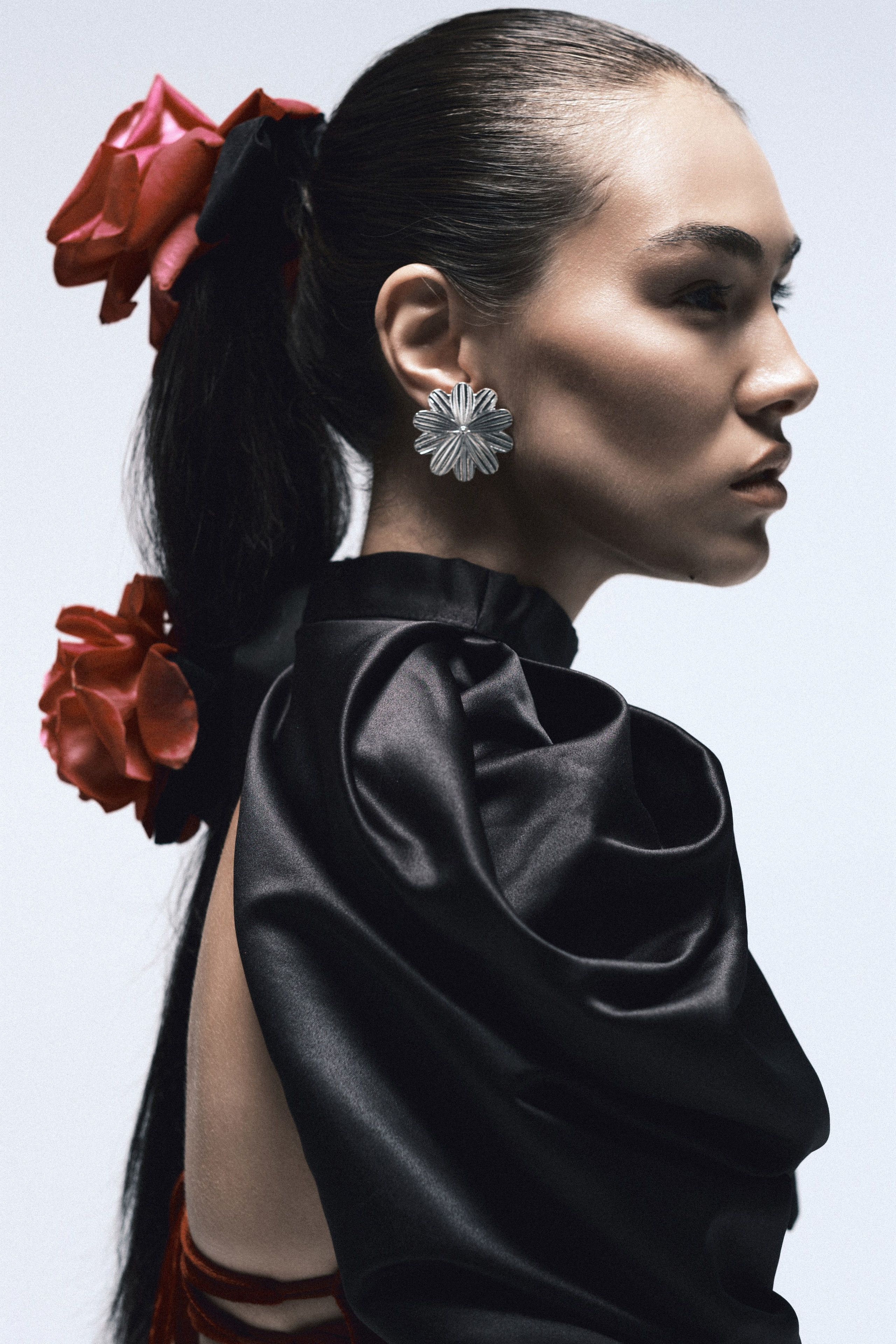 Профильный fashion-портрет модели с цветами в волосах и крупными серьгами, студийная съёмка в editorial стиле