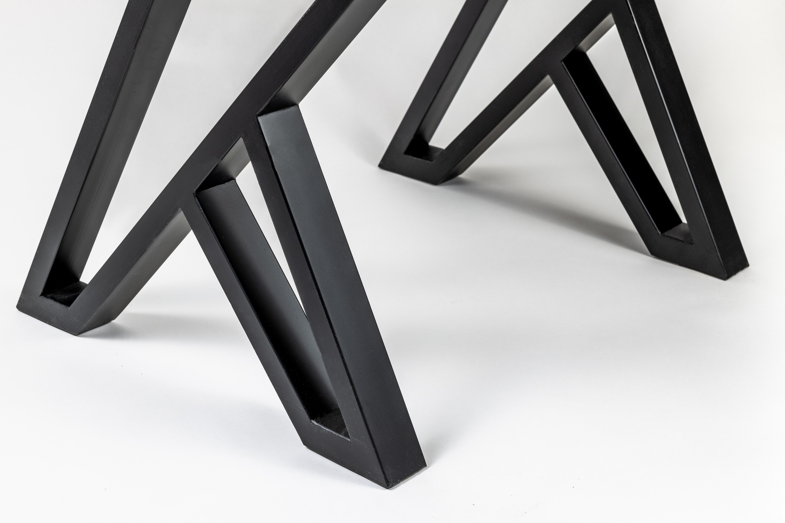 Крупный план ножек стола из черного металла в форме геометрических фигур на белом фоне