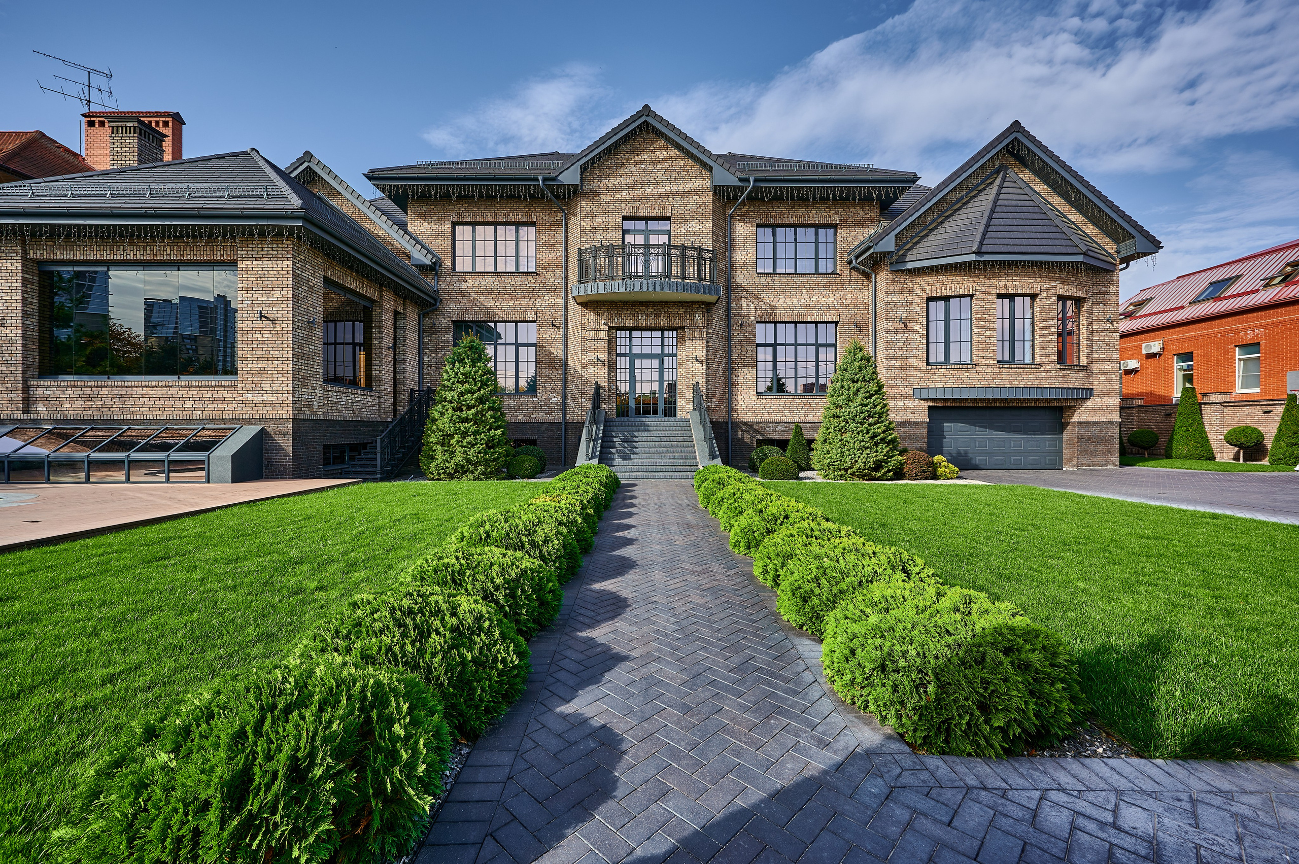 большой дом на земле из облицовочного кирпича с зелеными деревьями