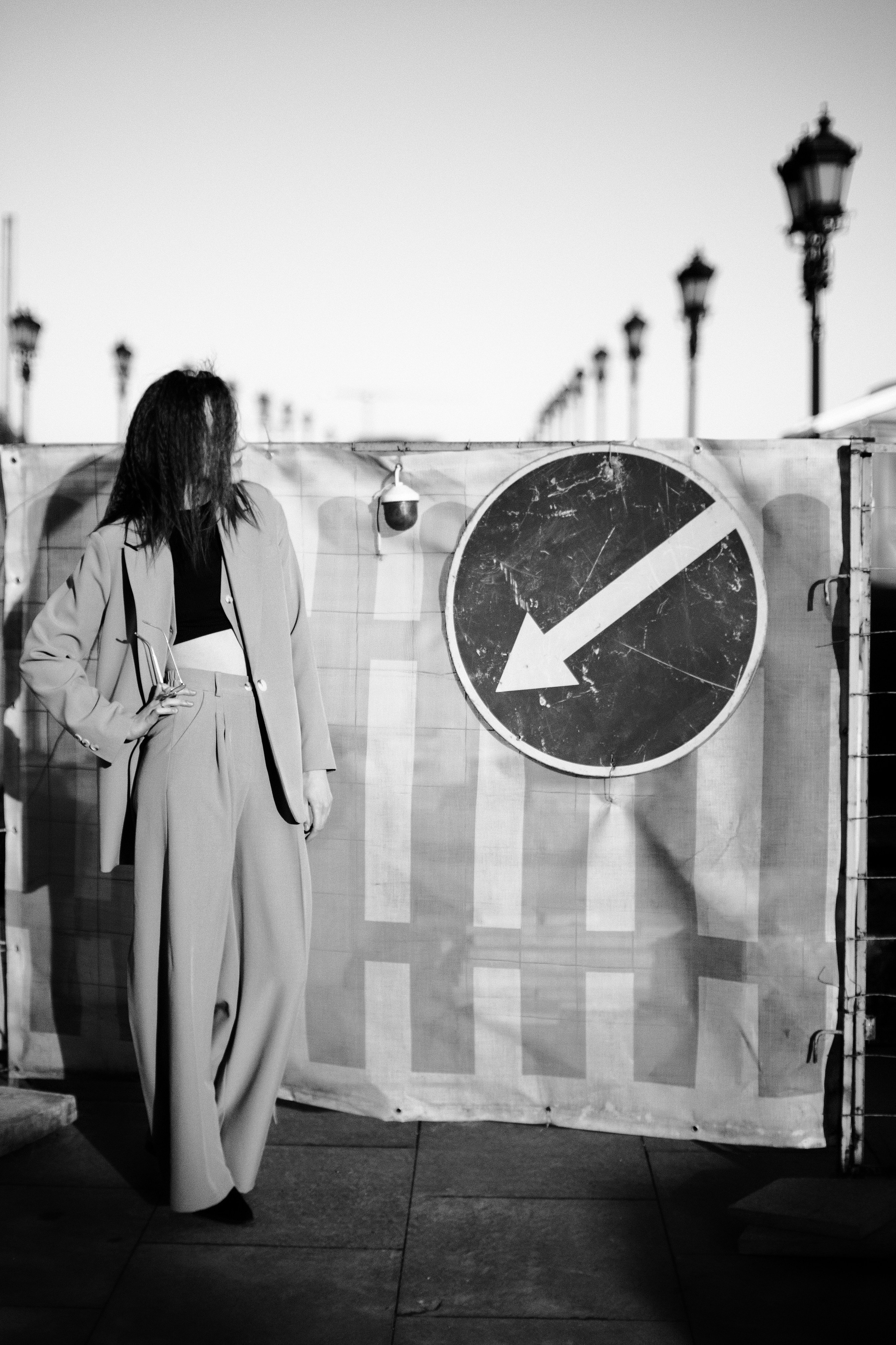 Черно-белый уличный портрет в бежевом костюме рядом с дорожным знаком, репортажная съемка, контрастное освещение